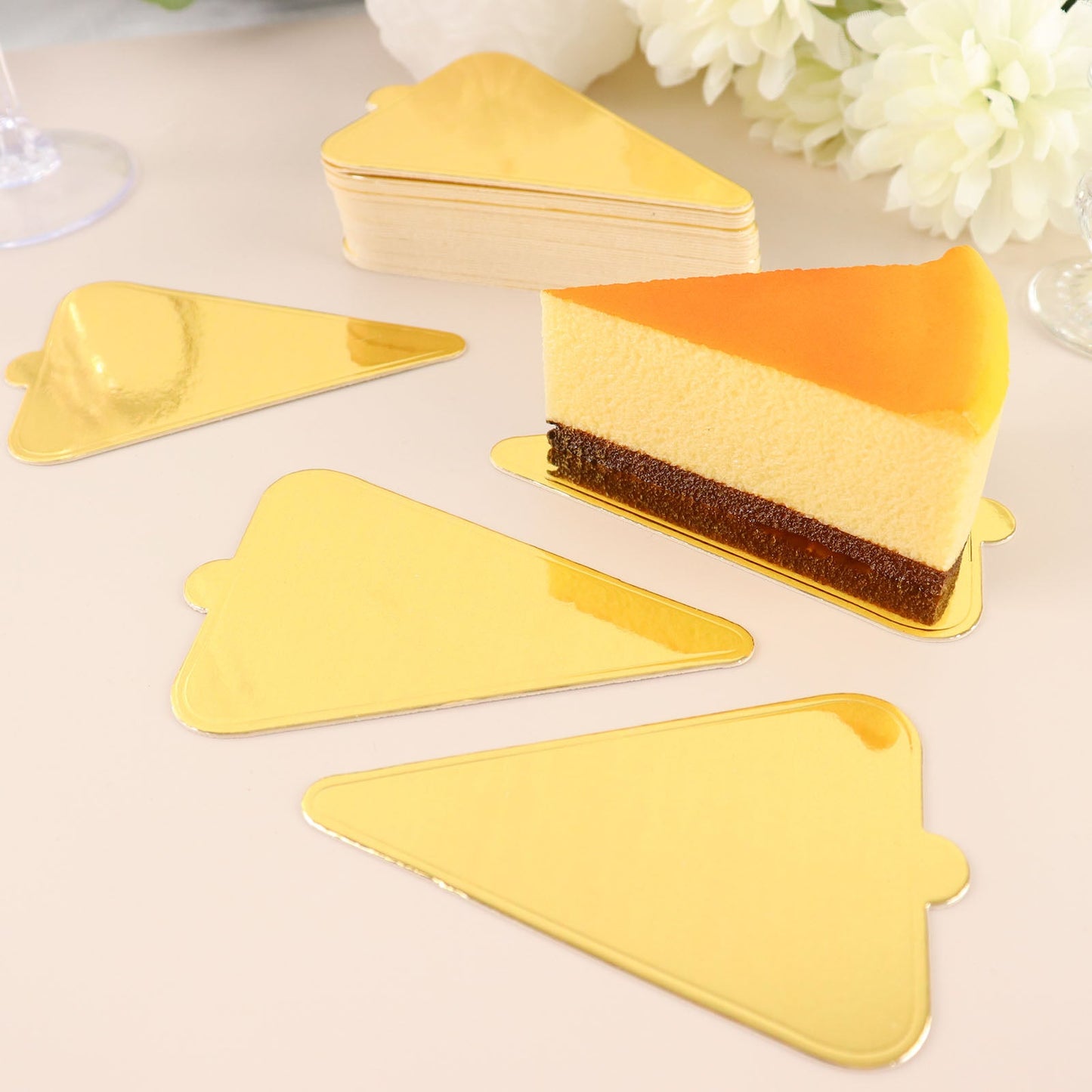 Mini gold triangle dessert slice trays with a cake slice on a light background.