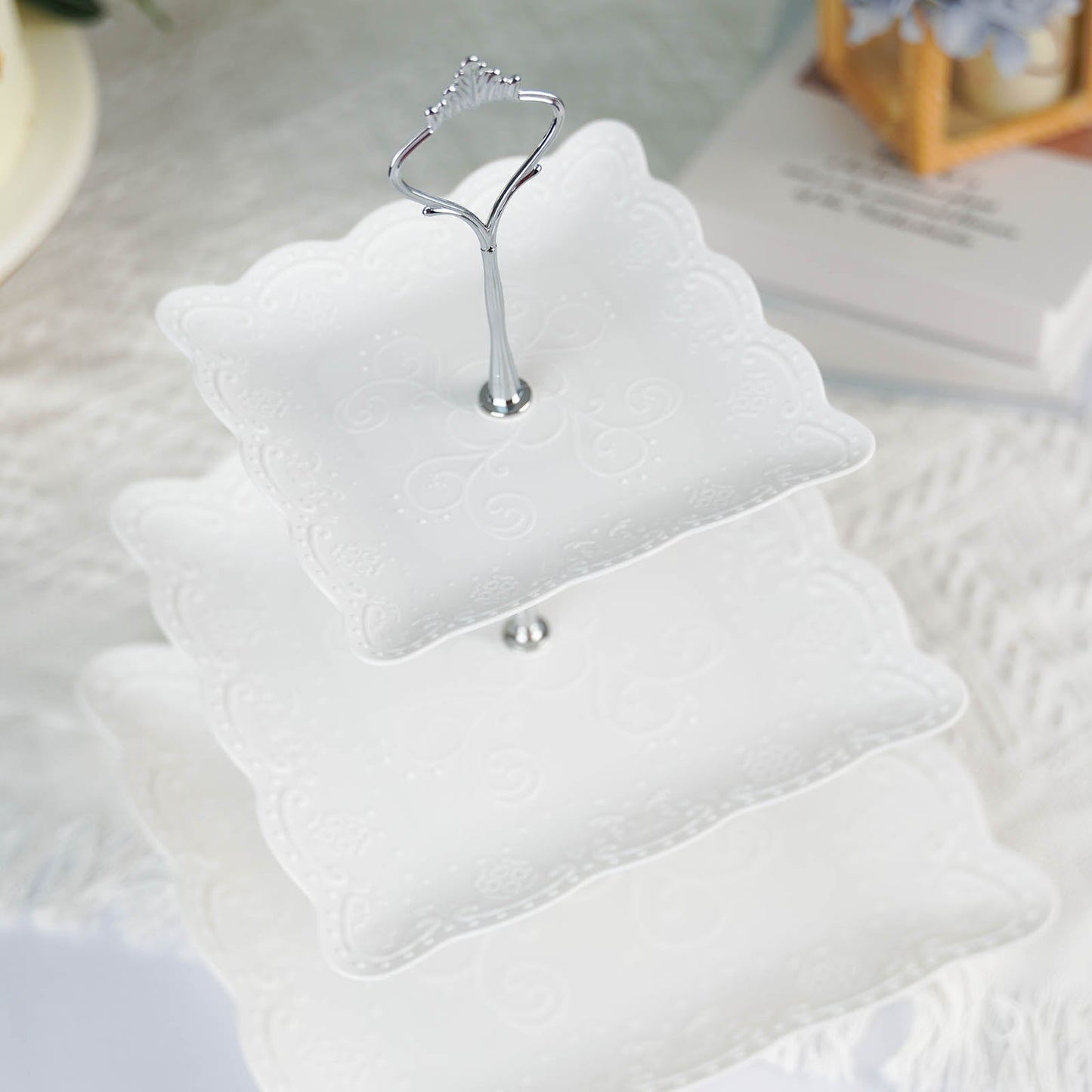 White 3-tier cupcake stand with floral embossed design and silver handle.