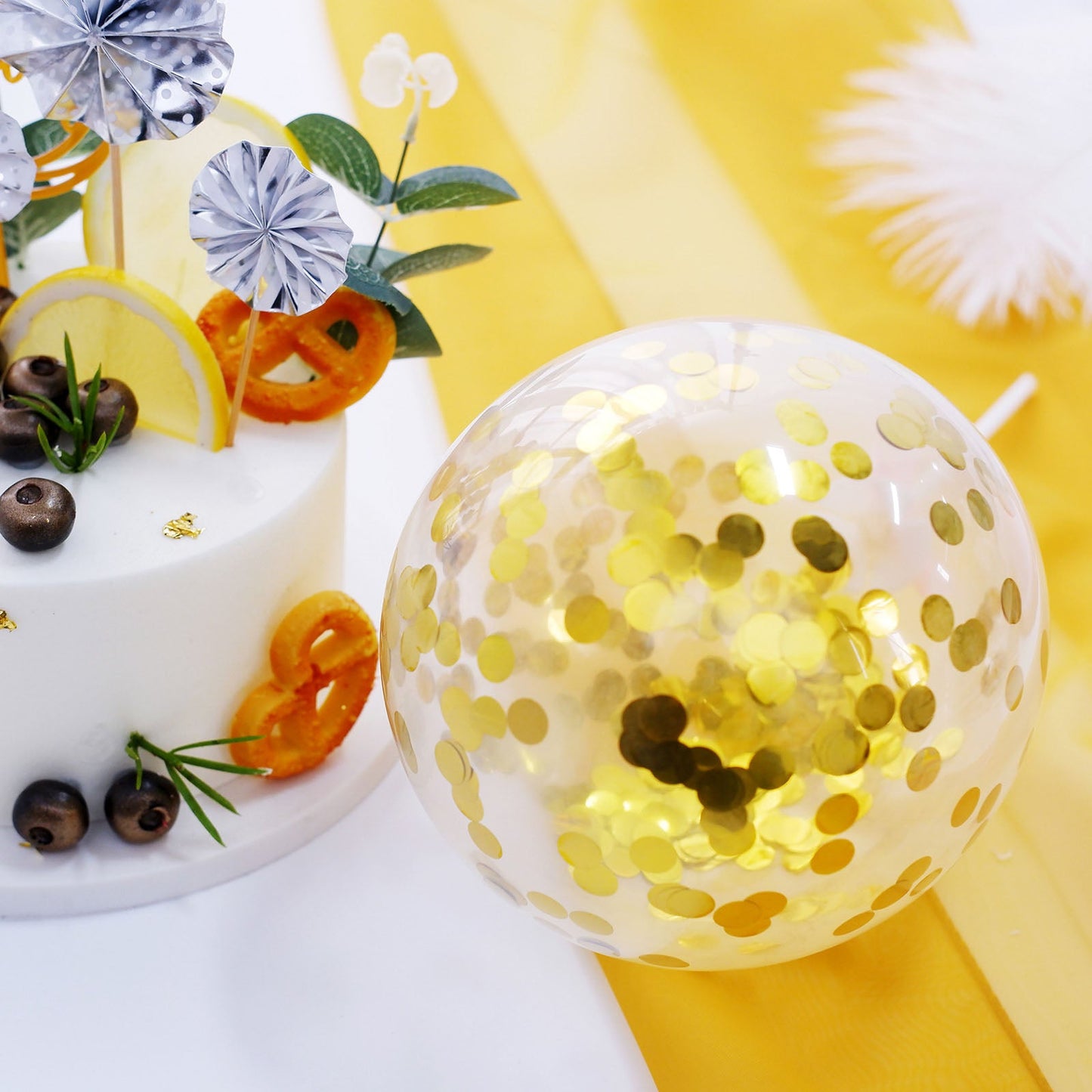 Gold confetti balloon and silver cake topper on a decorated table.