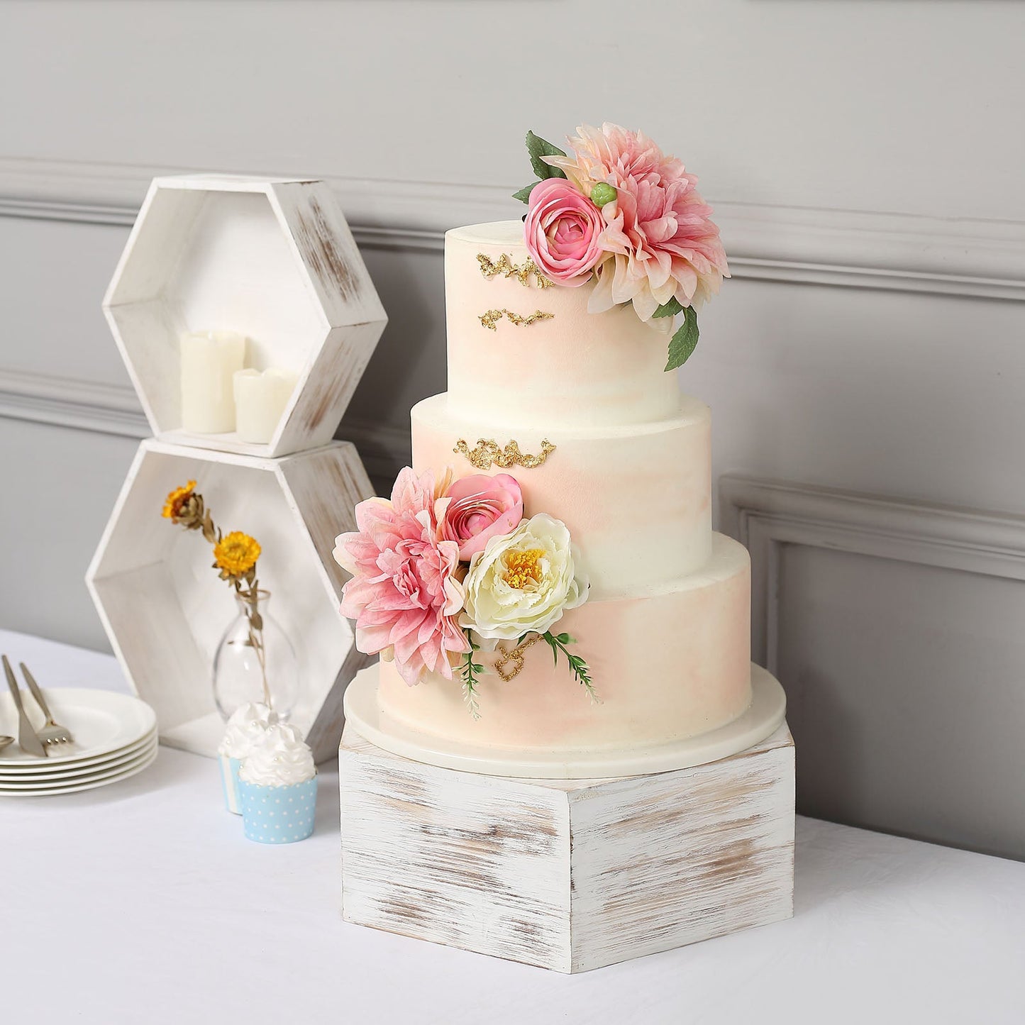 Whitewashed hexagonal wooden dessert holder display boxes stacked beside a decorated cake.