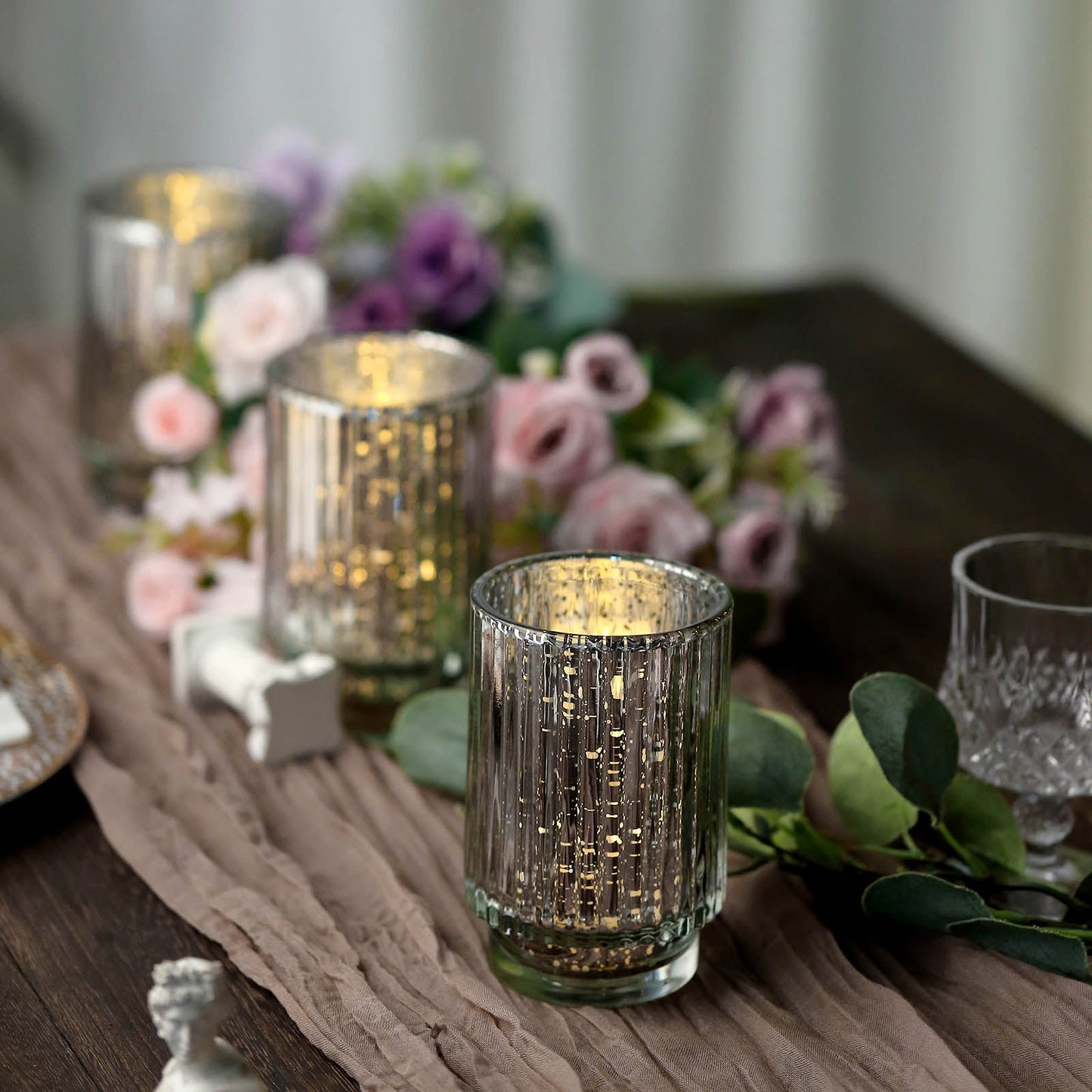 Silver mercury glass votive candle holders with a wavy column design.