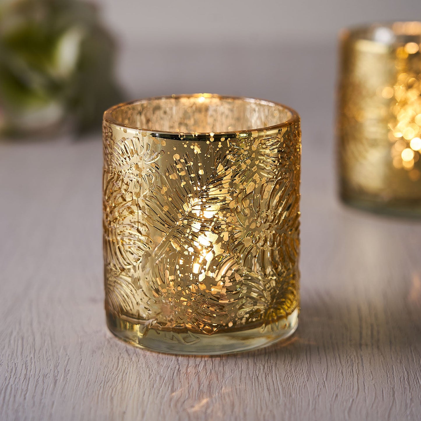 Gold mercury glass palm leaf candle holder with intricate design.