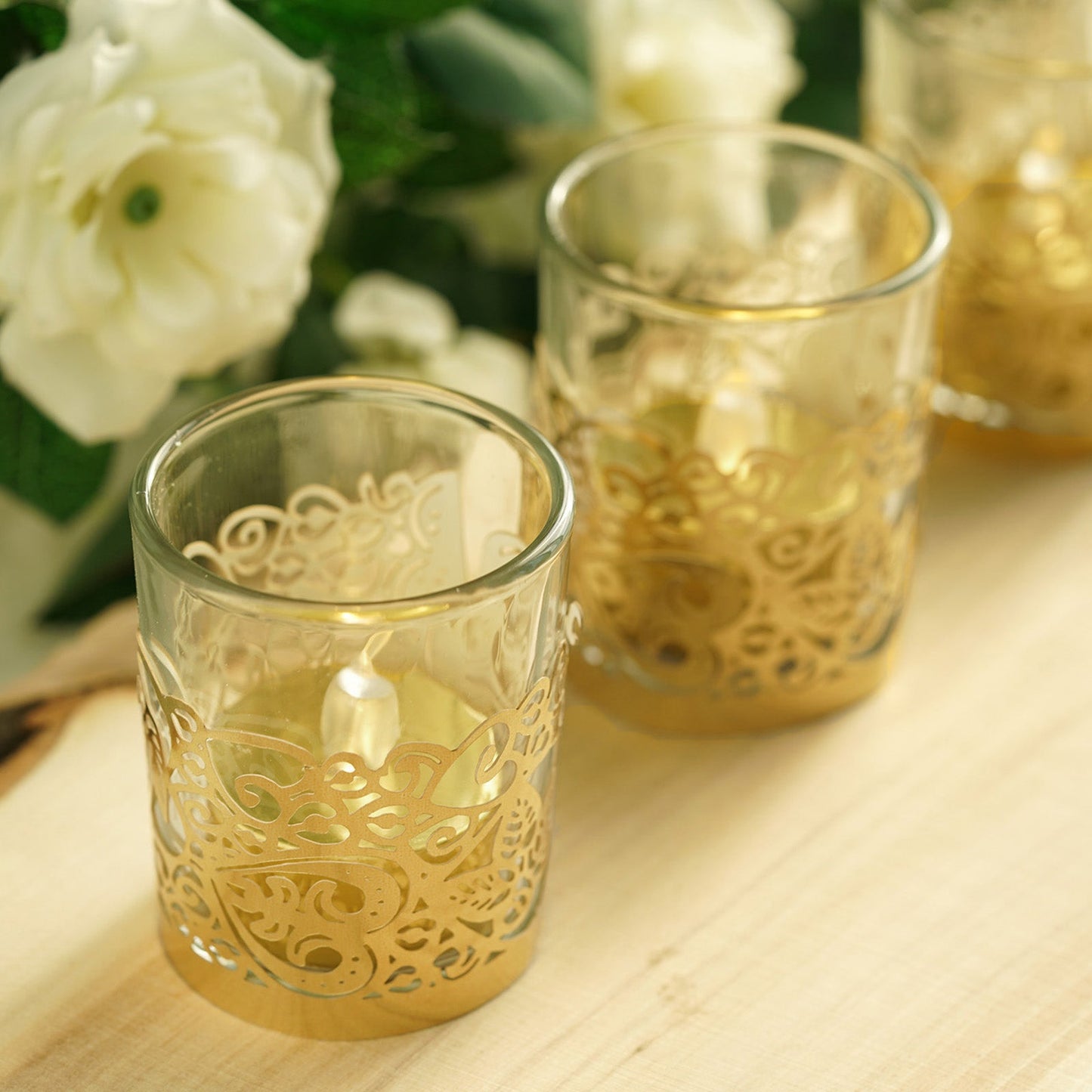 Gold foil floral lace candle holder wraps with tealight candles.