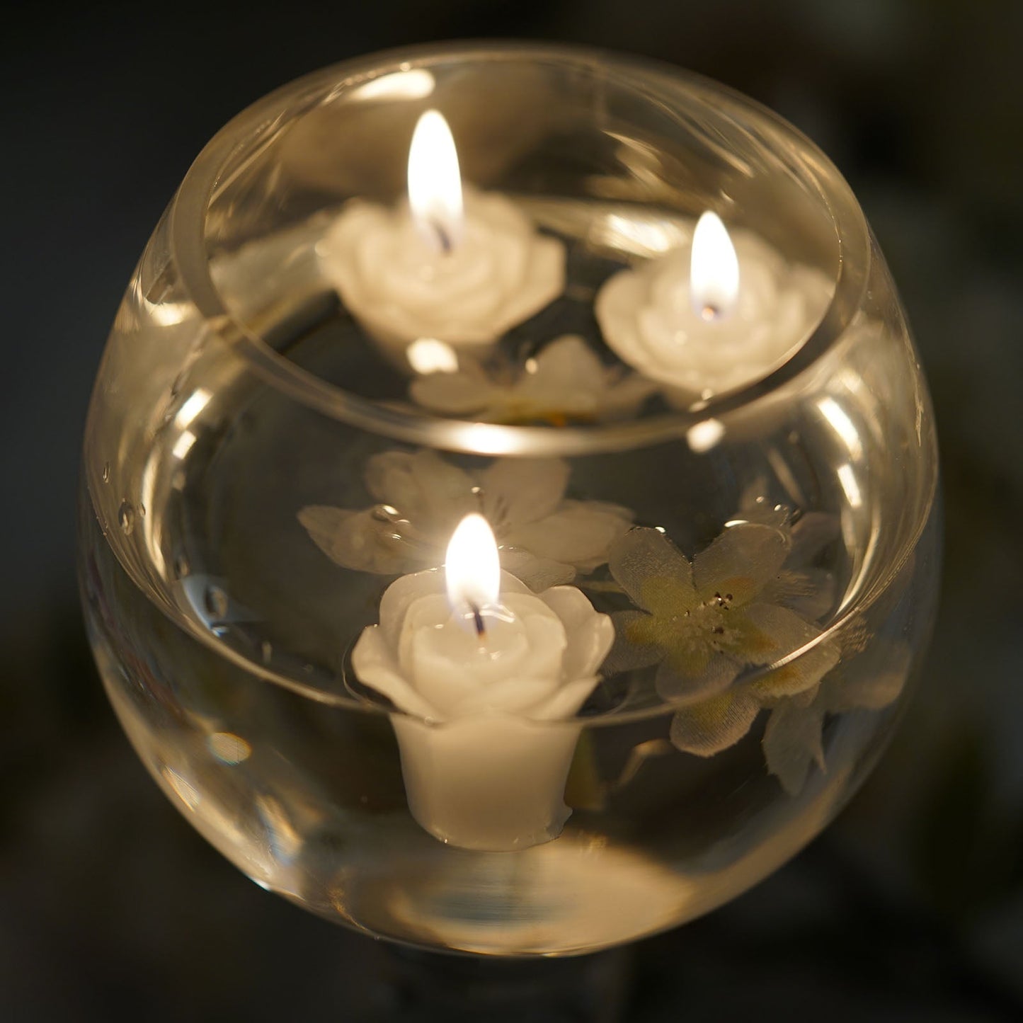 Ivory mini rose floating candles in a glass vase.