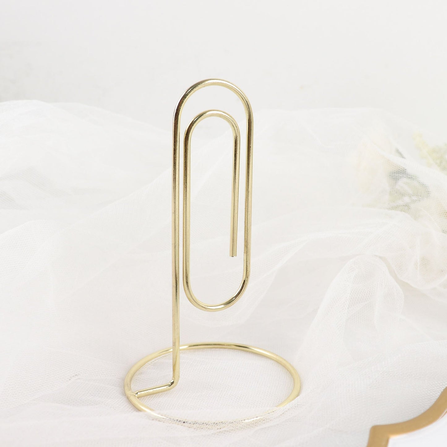 Gold metal paperclip card holder stand for table numbers and menus.