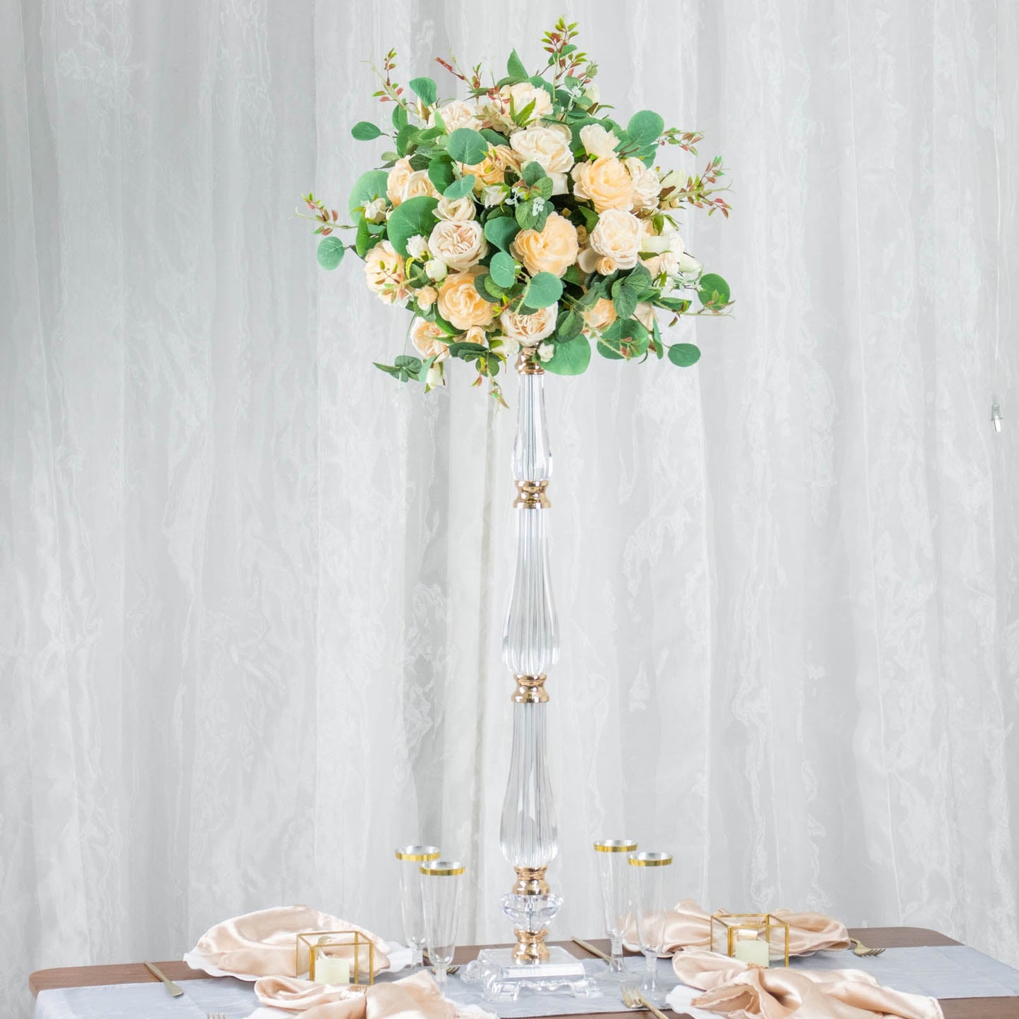 Gold acrylic crystal pillar candle stand centerpiece with floral arrangement.