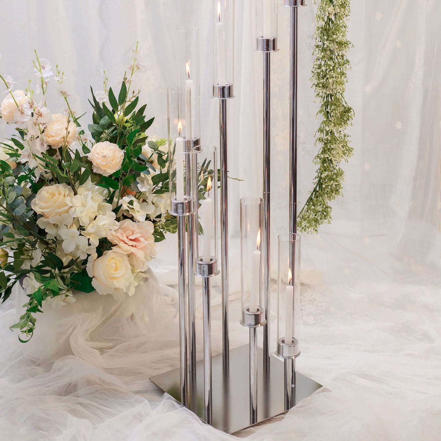 Silver 8 arm cluster candle holder with clear glass shades and floral arrangement.