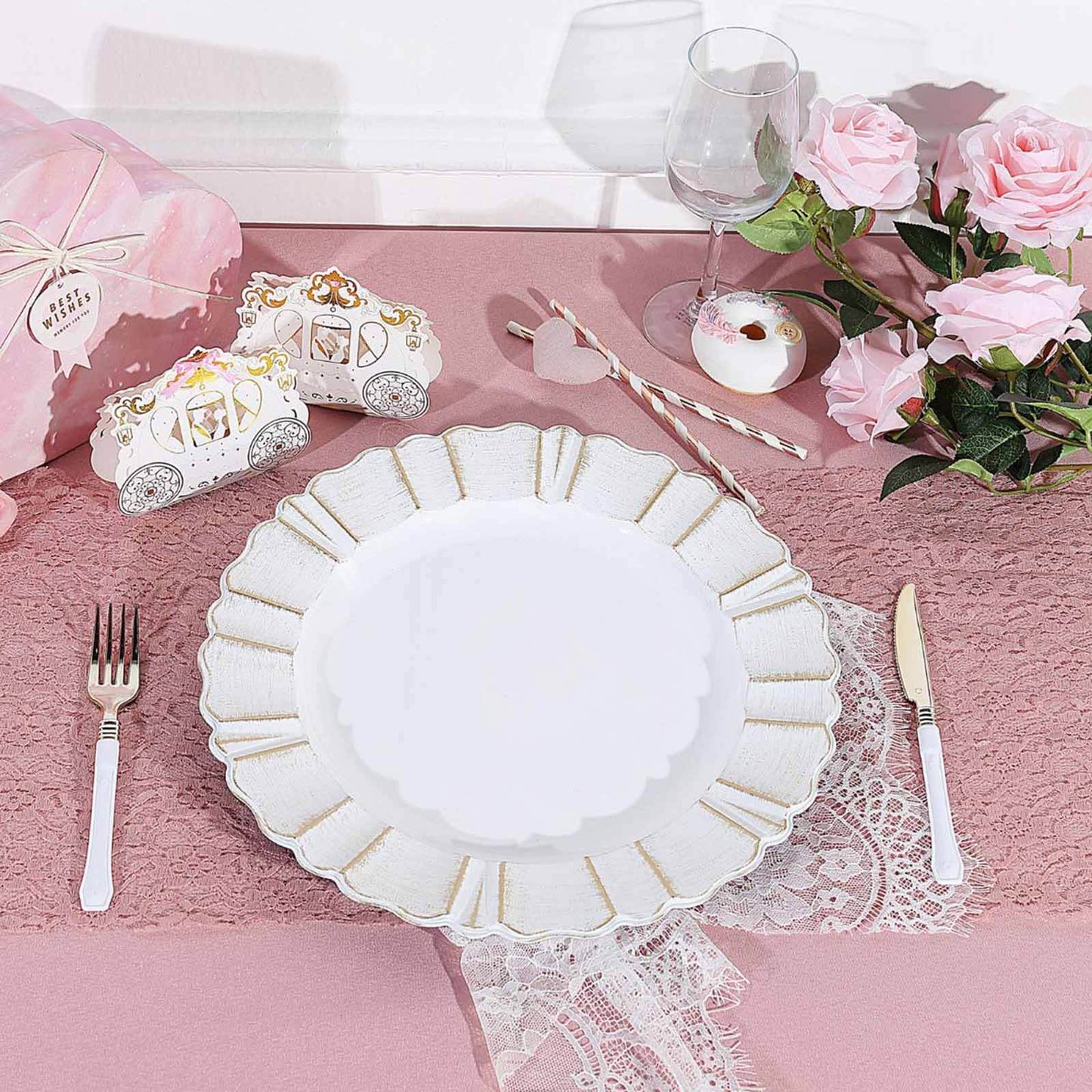 White charger plate with gold brushed wavy scalloped rim on a pink table setting.