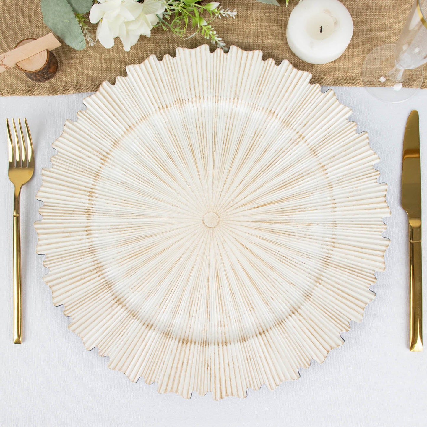 Antique white round charger plate with sunray scalloped rim on a table setting.