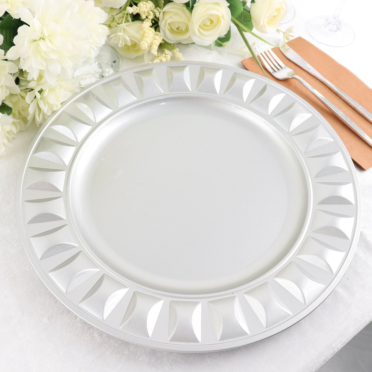 Silver round bejeweled rim disposable charger plate on a table setting.