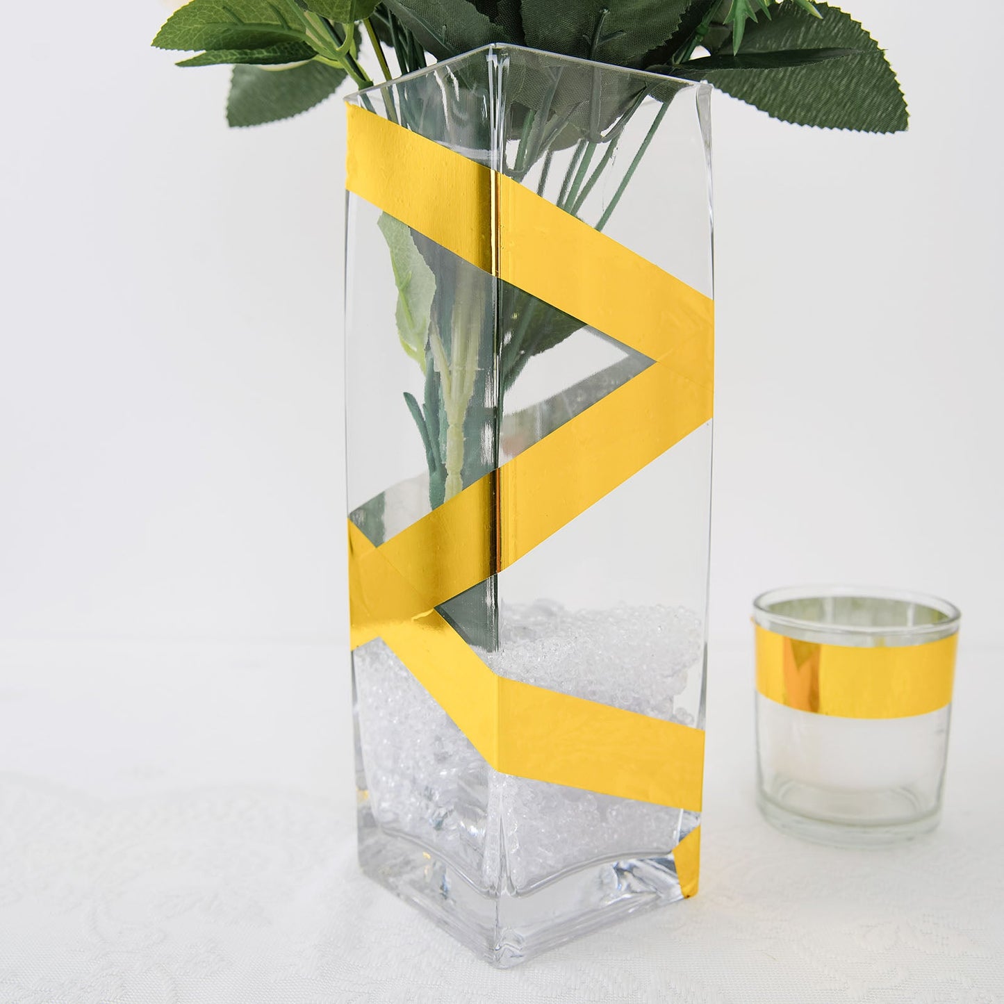 Gold metallic tape used decoratively on a clear vase with flowers.
