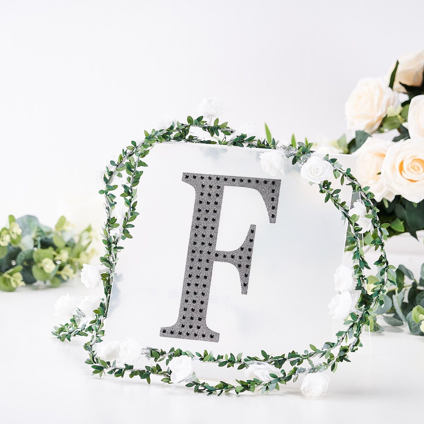 Black decorative rhinestone letter "F" with floral accents.