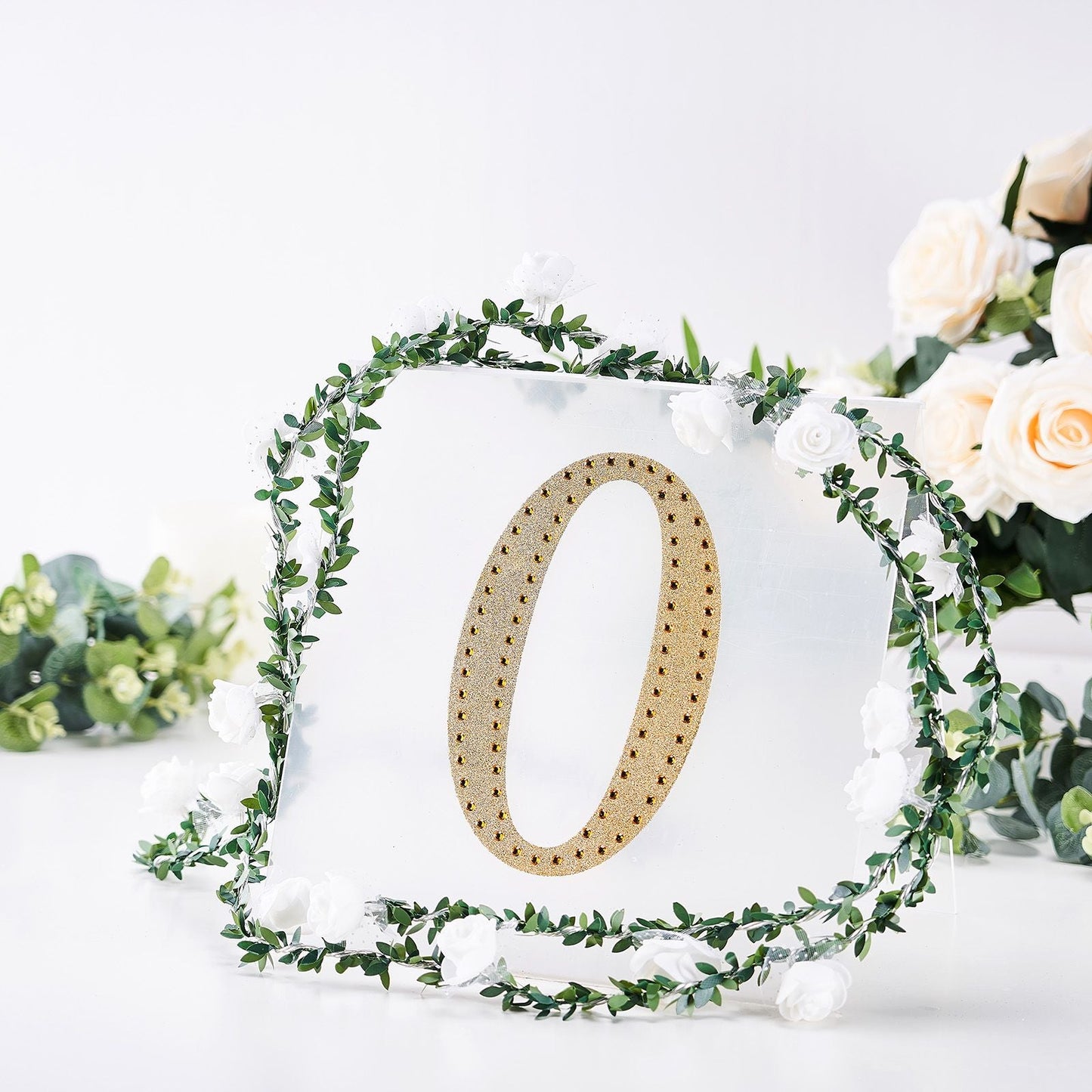 Gold decorative rhinestone letter "O" sticker on a clear background with flowers.