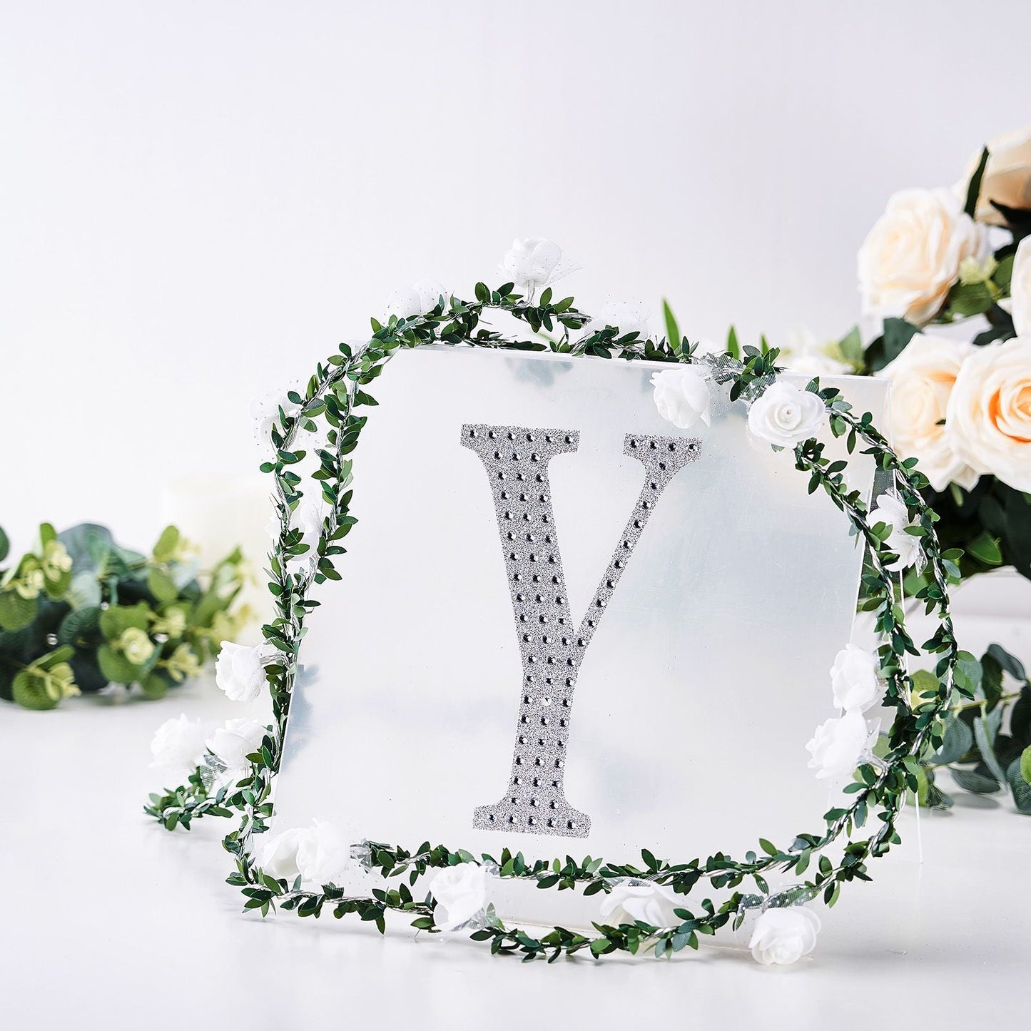 Silver decorative rhinestone letter Y surrounded by flowers.