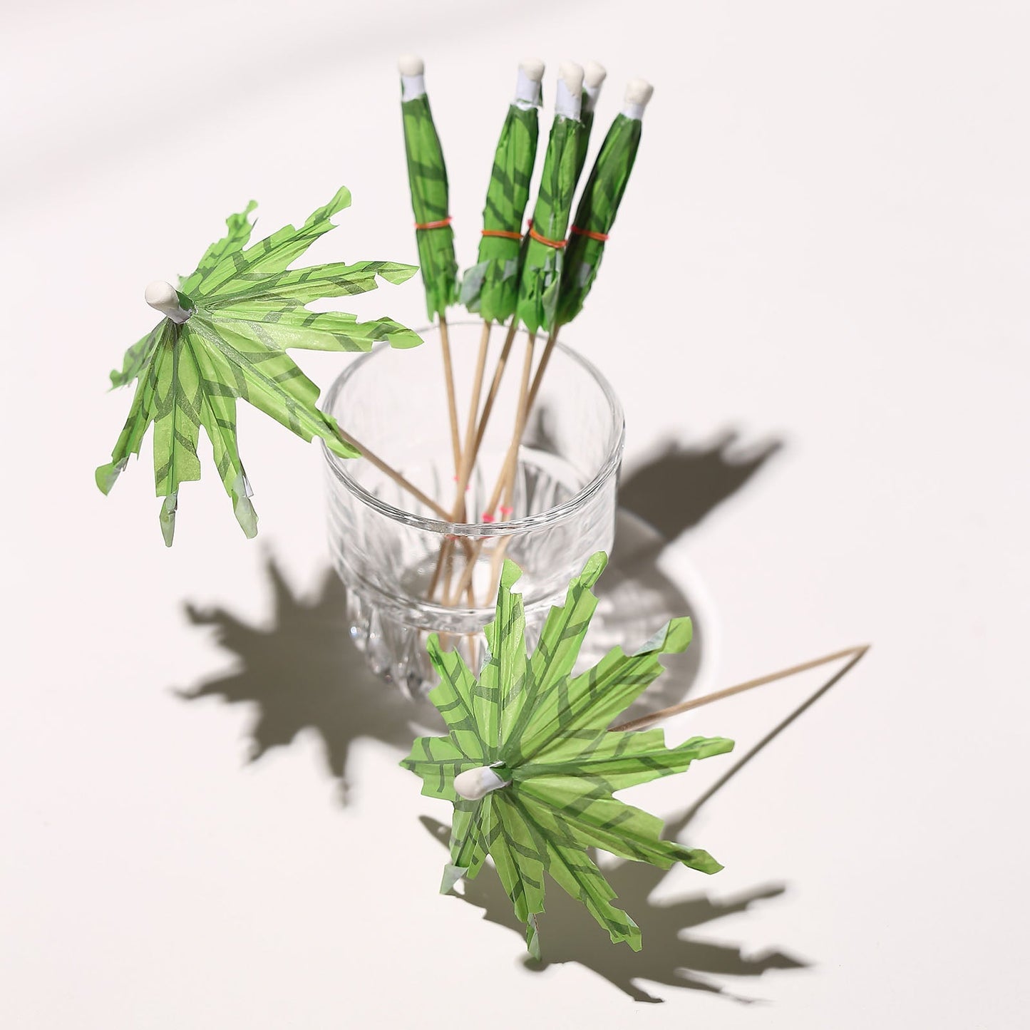 6" green tropical leaf cocktail drink umbrella picks in a glass.