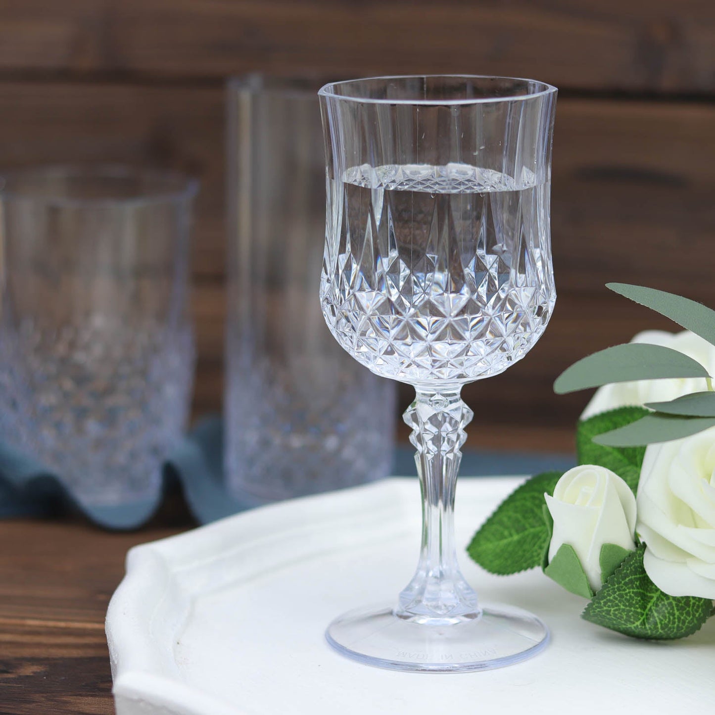 Clear crystal cut reusable plastic cocktail goblet on a tray.