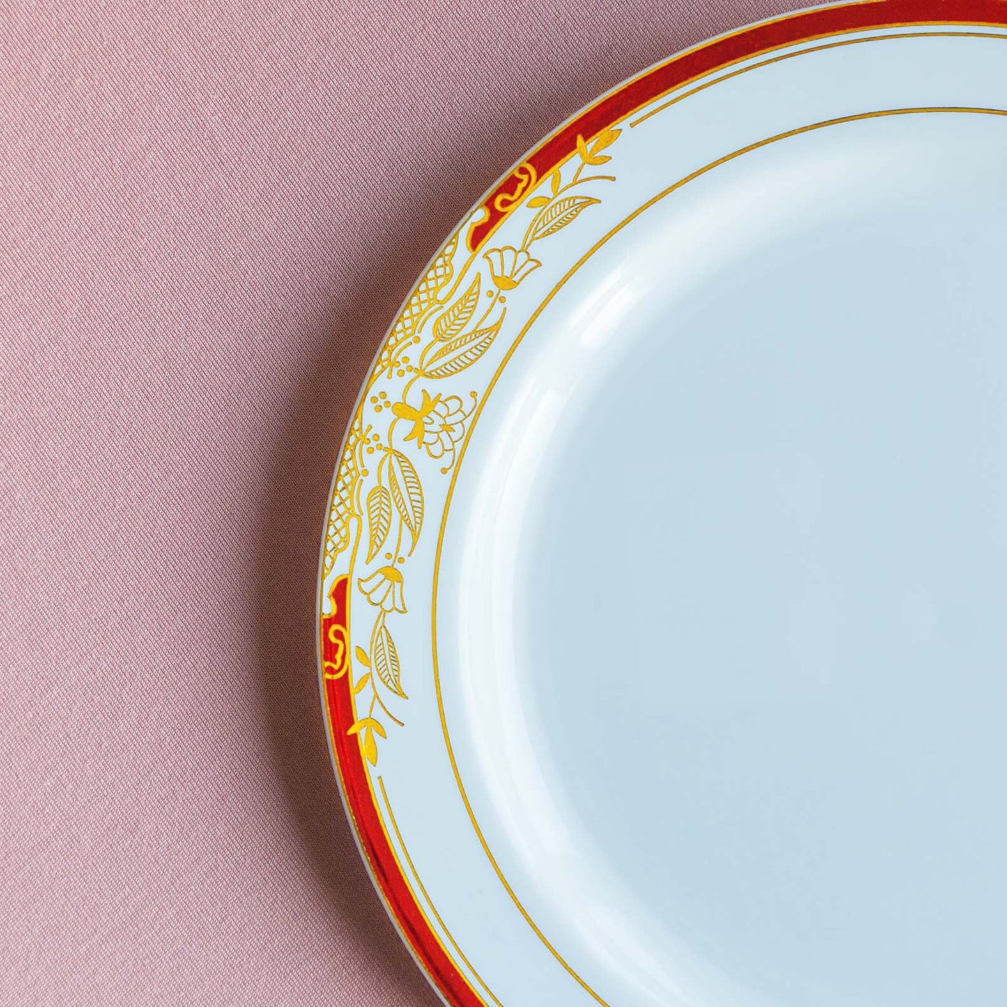 White dinner plate with red rim and gold vine design.