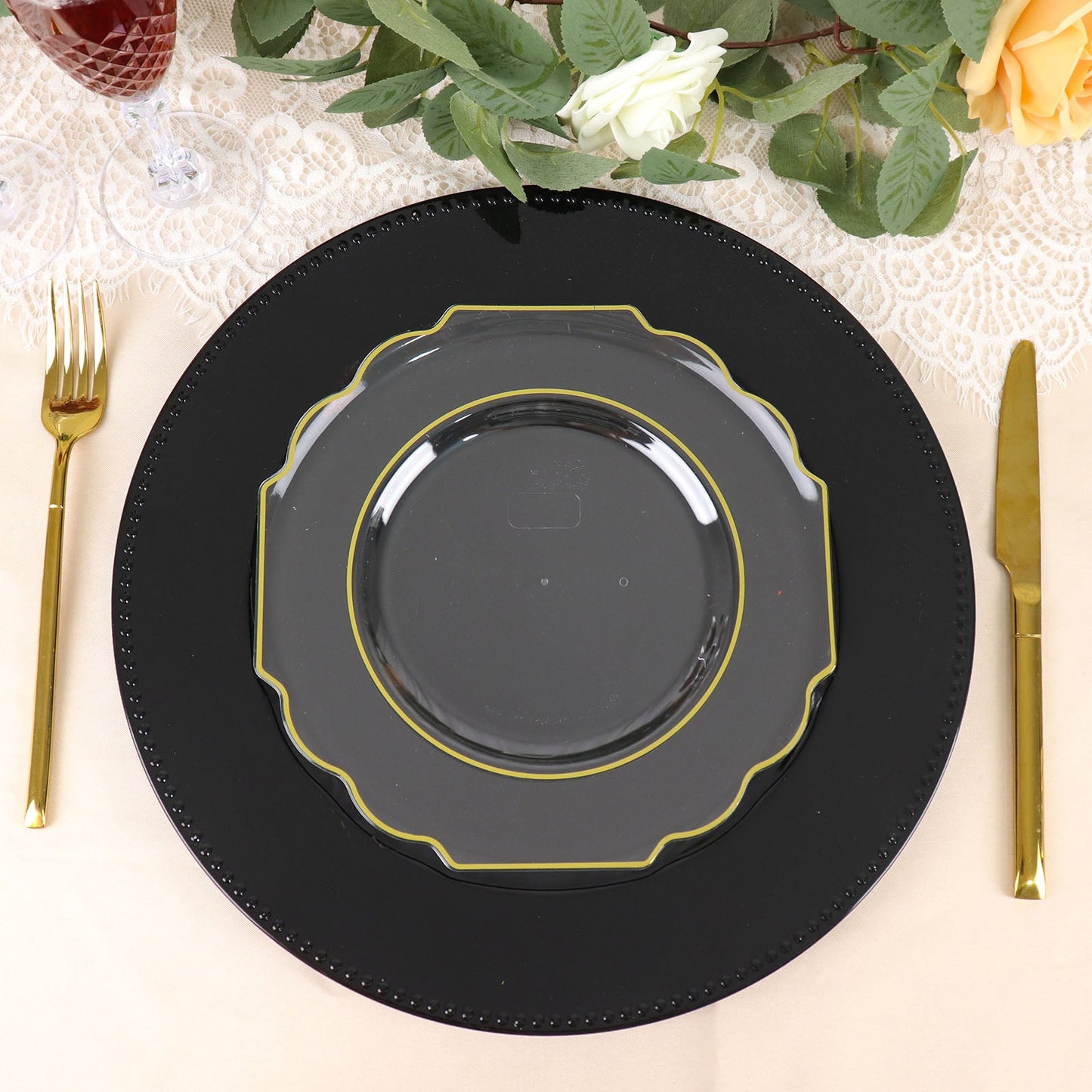 Clear hard plastic dessert plate with gold rim on a black charger.