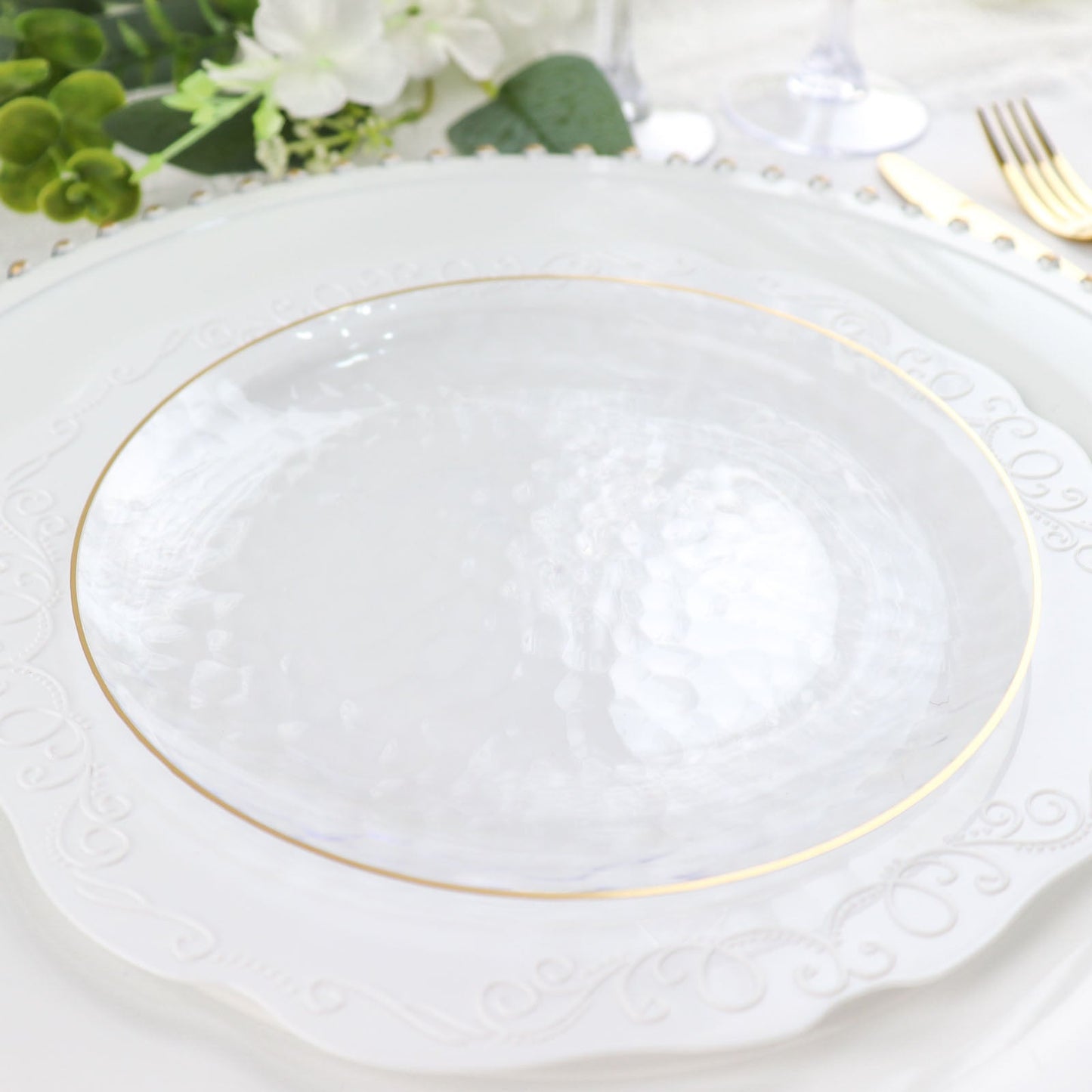 Clear hammered round plastic plate with gold rim.