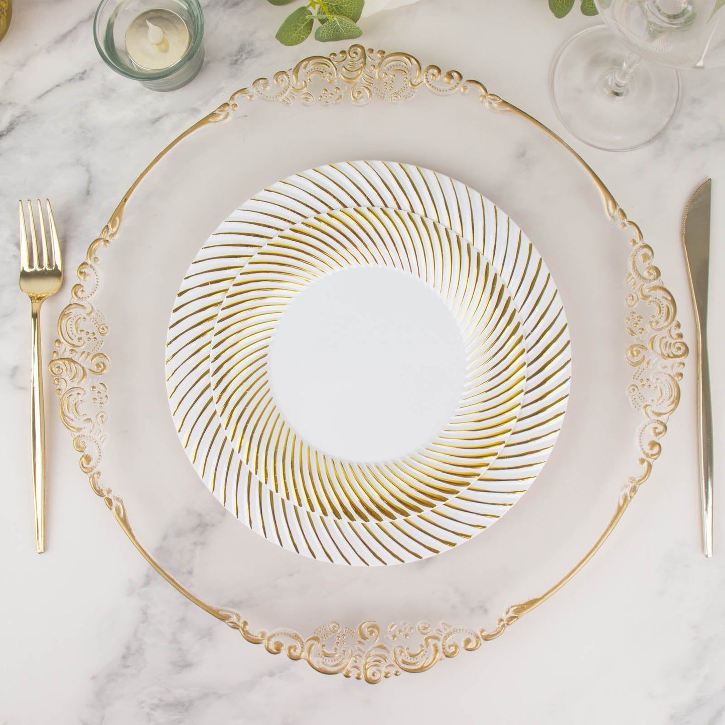 White plastic party plates with gold swirl rim on a marble table.