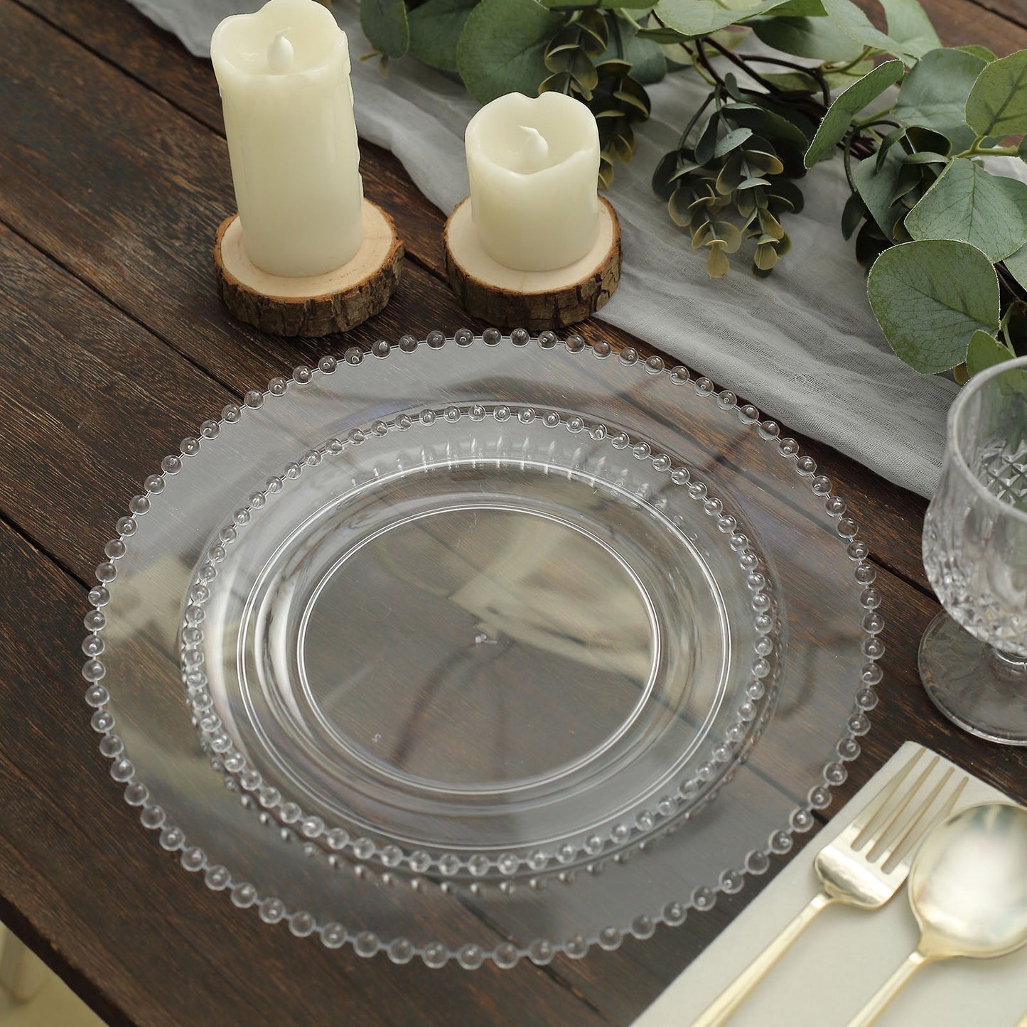 Clear plastic dessert plates with beaded rim on a wooden table.