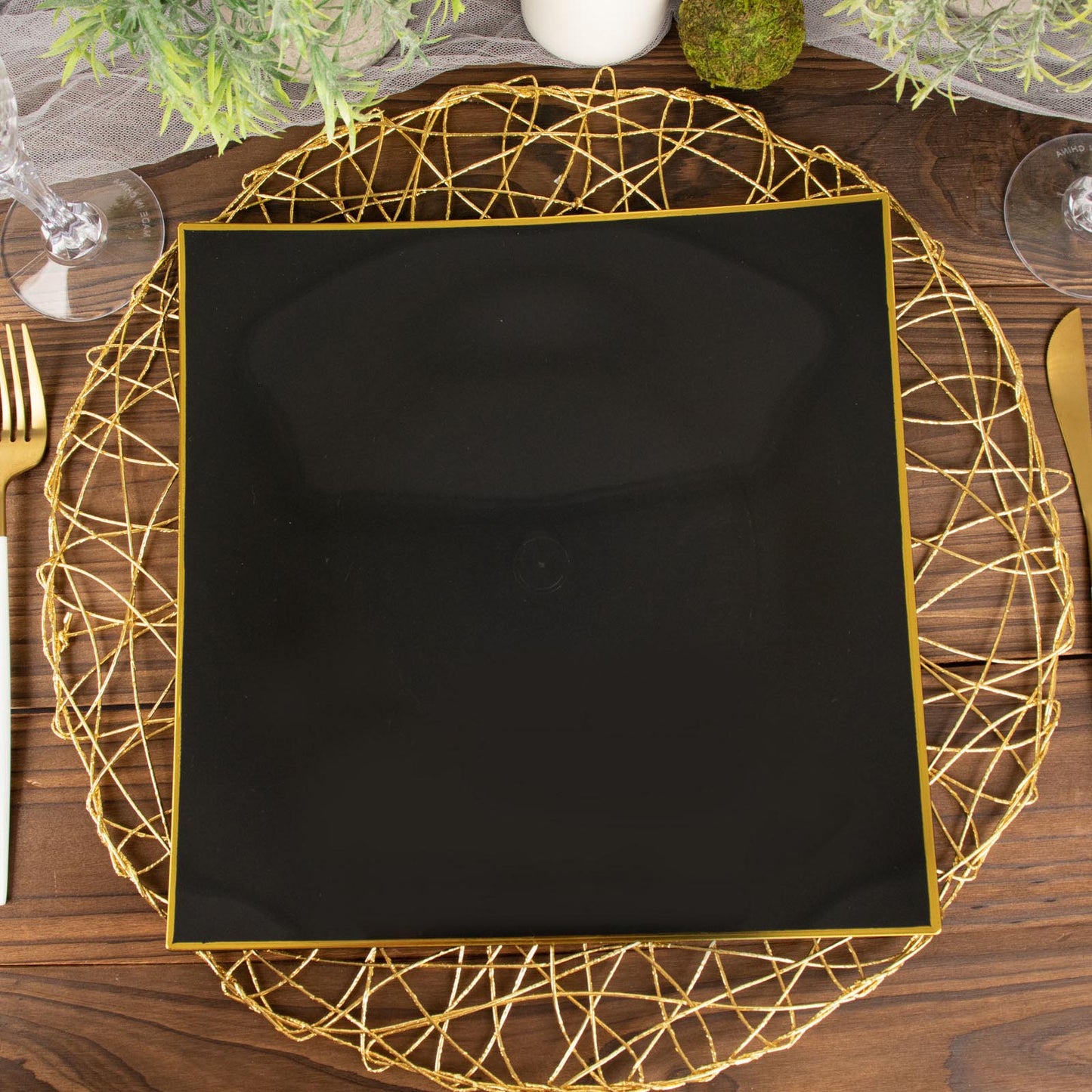10" black and gold concave modern square disposable dinner plate on a decorative charger.