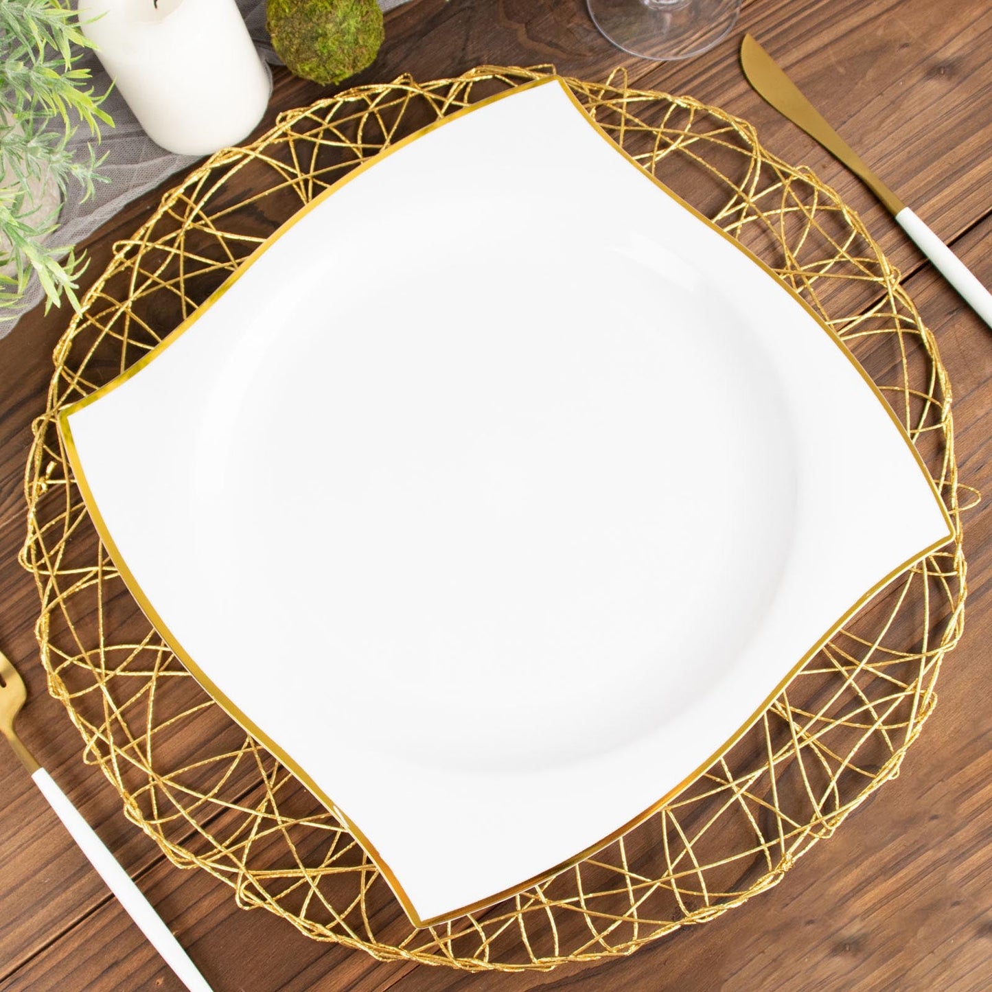 10" white and gold wavy rim square disposable dinner plate on a decorative charger.