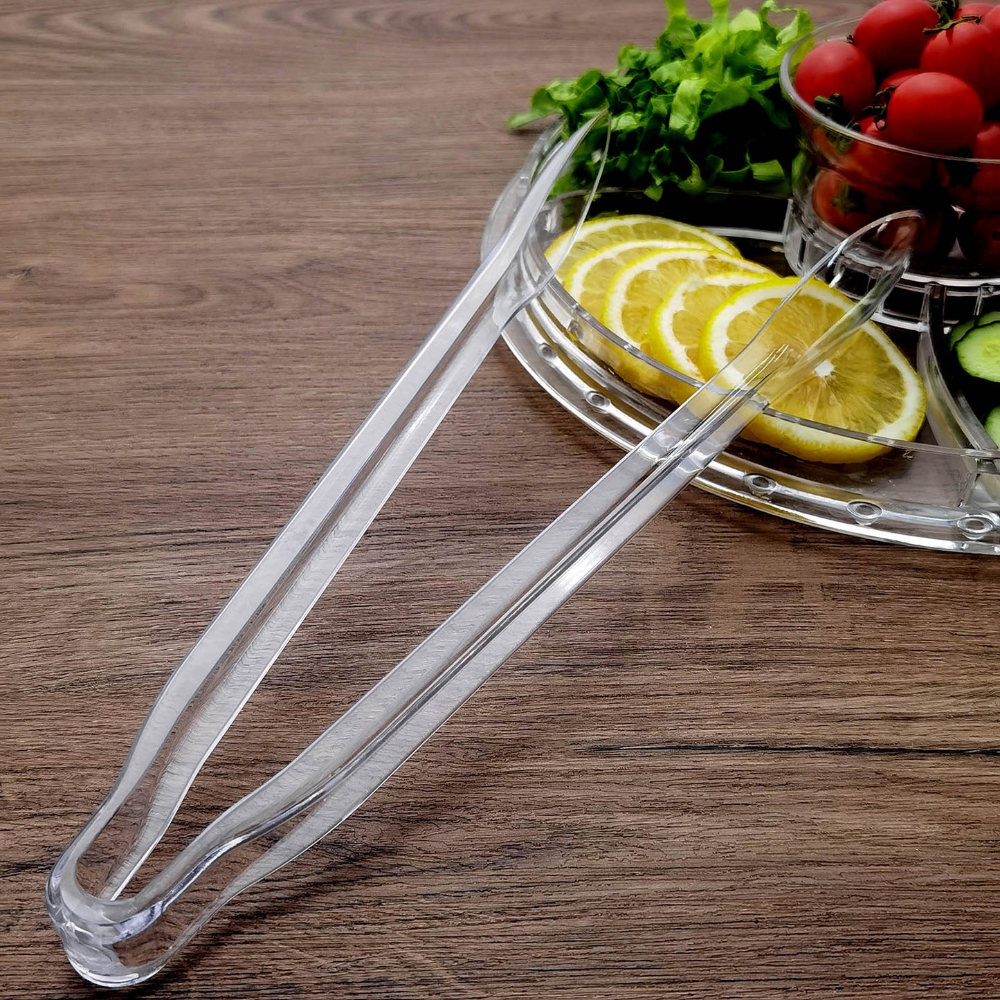 Silver metal kitchen tongs with scalloped edges on a wooden surface.