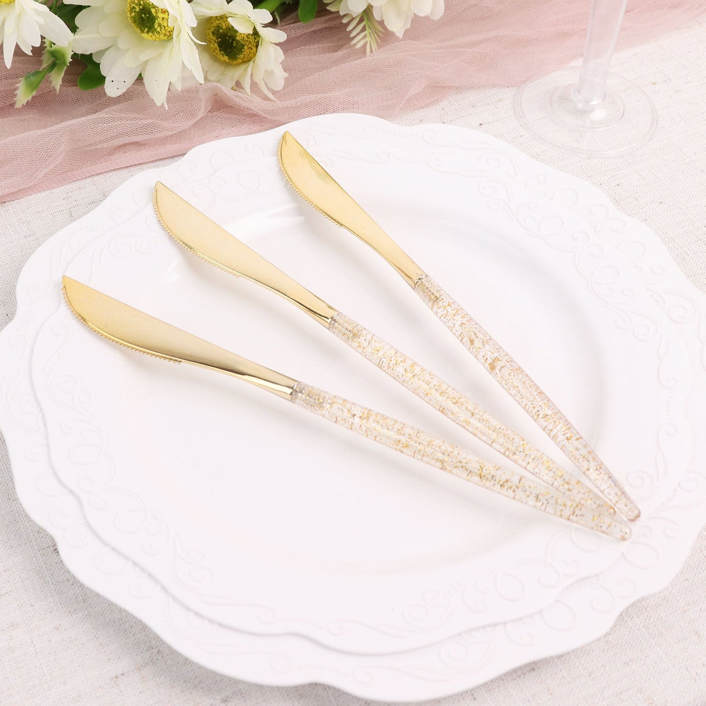Gold glittered disposable knives on a plate.