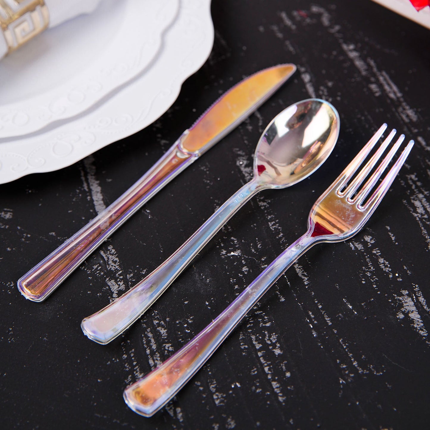 Iridescent disposable cutlery set on a black surface.
