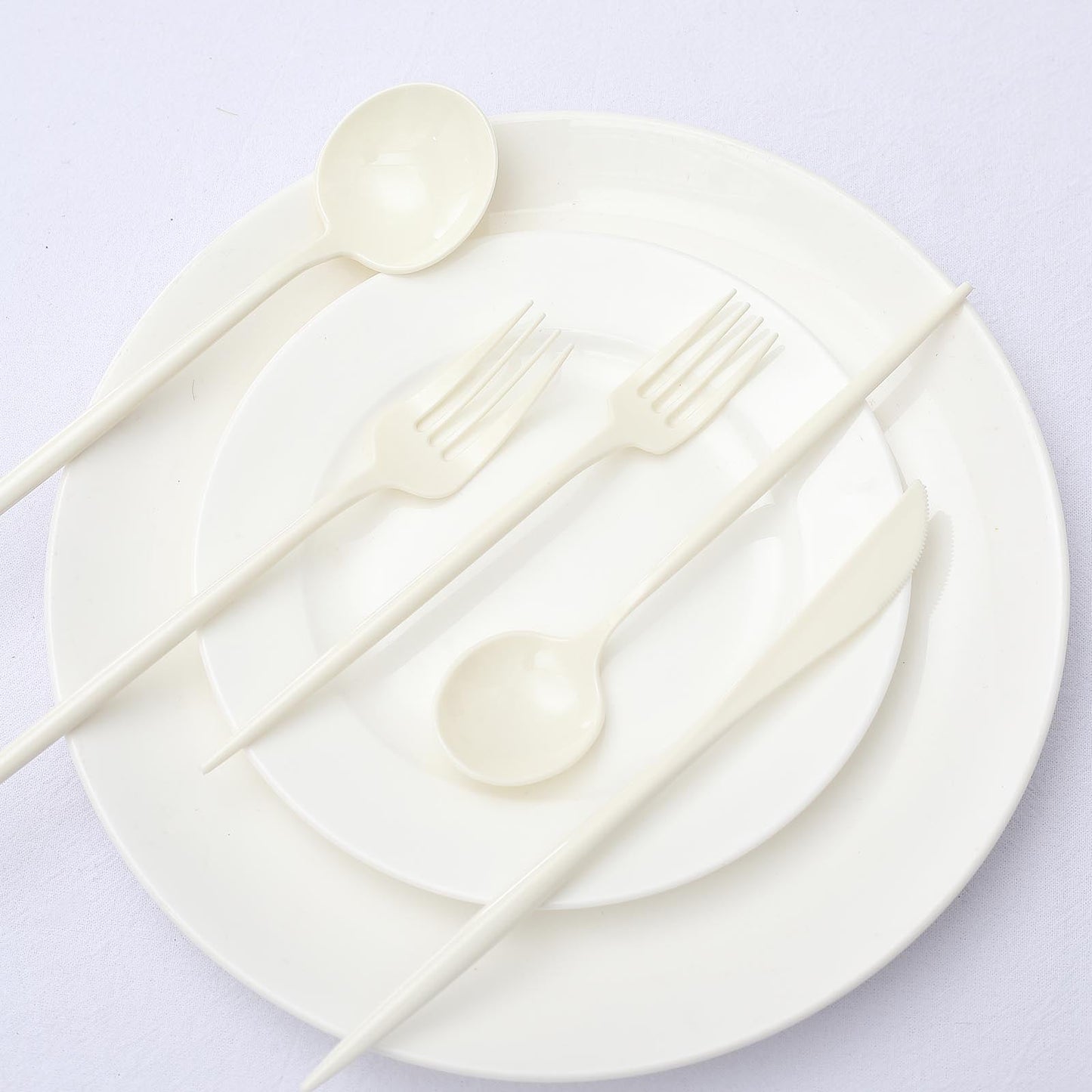 Ivory disposable cutlery set on white plates.