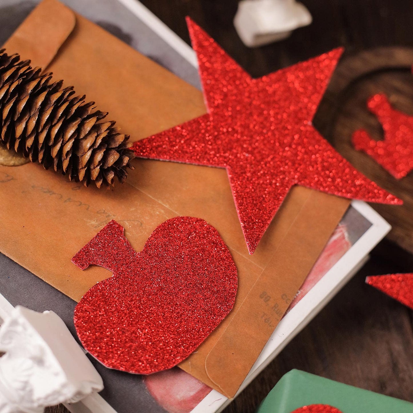 Red glitter DIY craft foam shapes on a wooden surface.