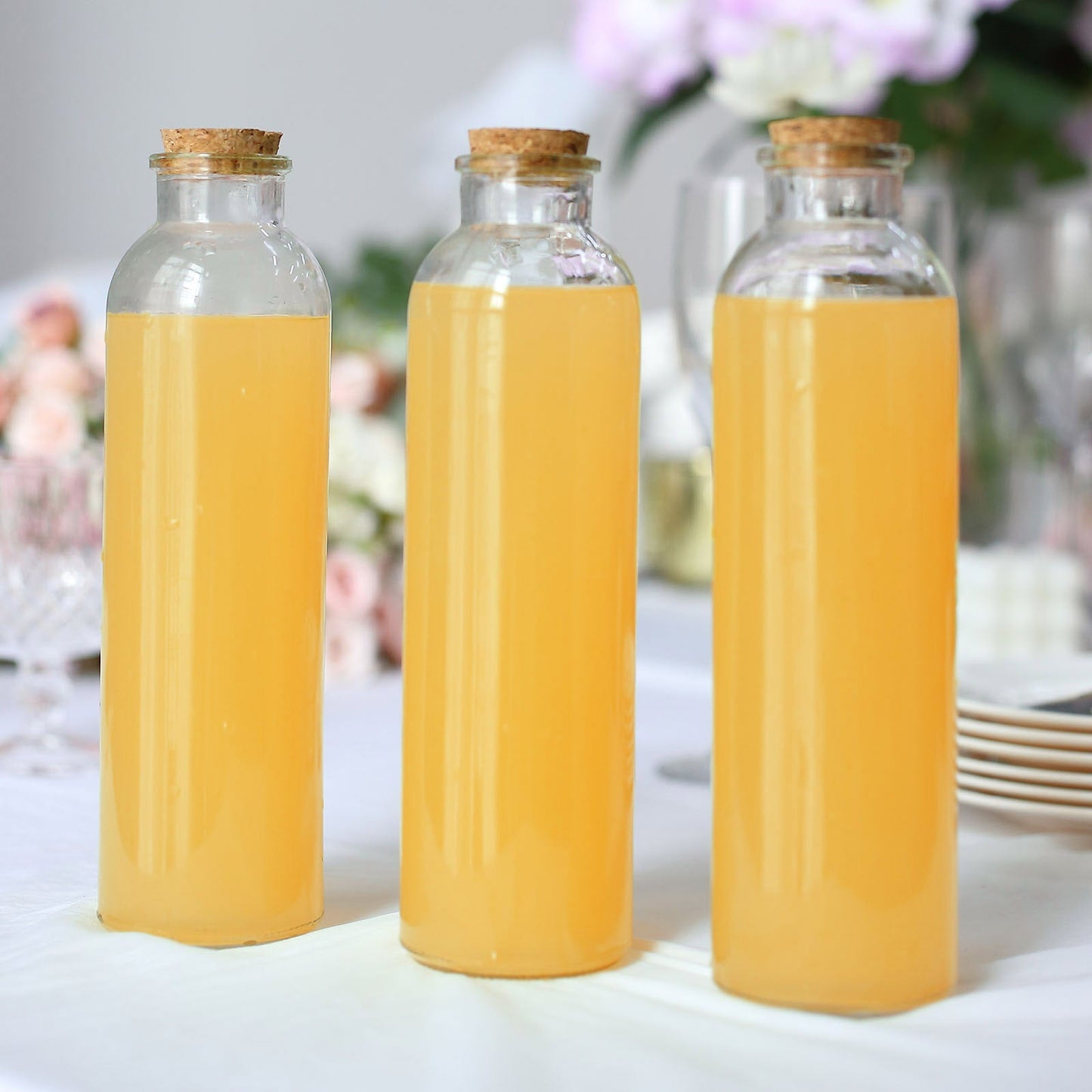Clear glass storage jars with cork stoppers, filled with yellow liquid.