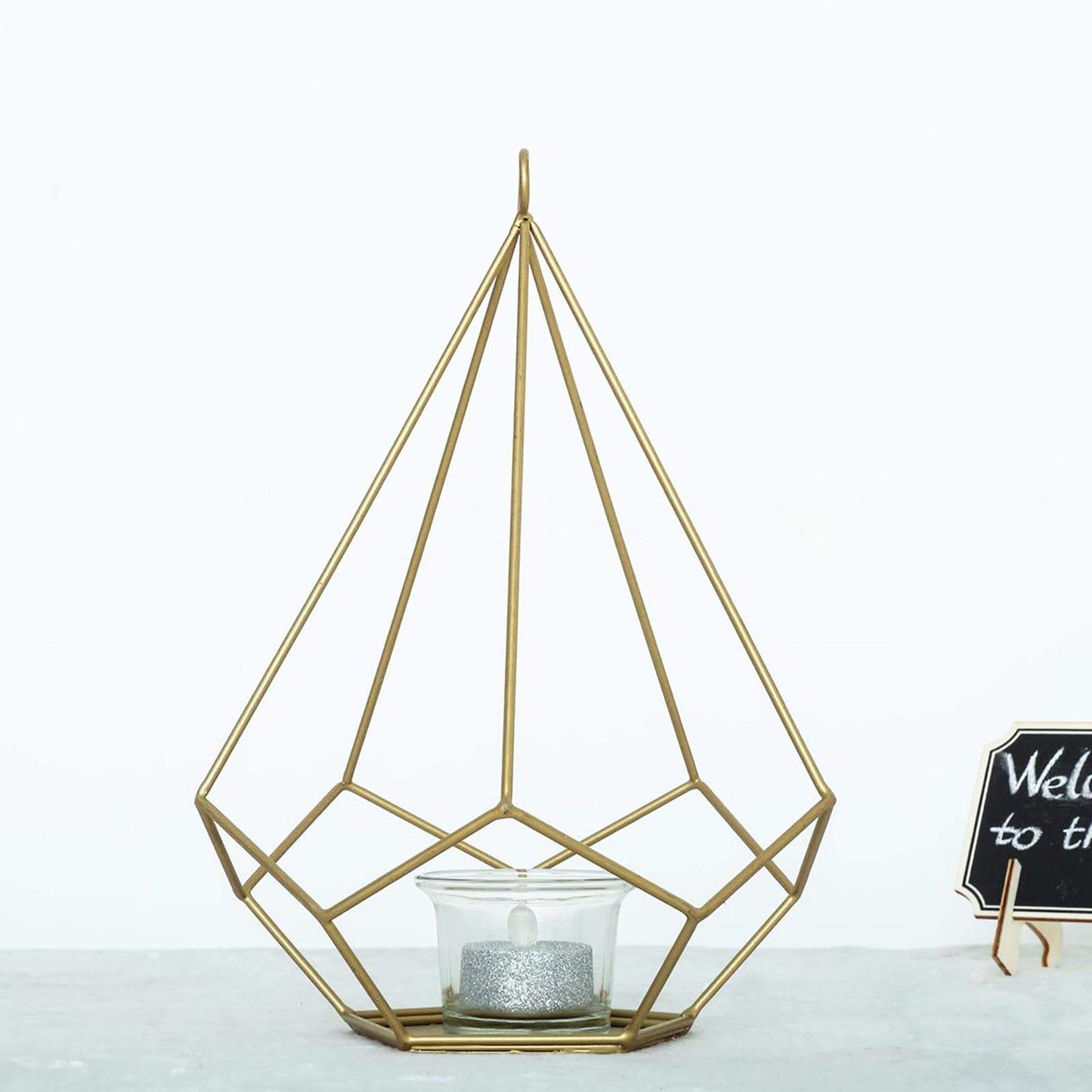 Gold geometric tealight candle holder with open frame design.