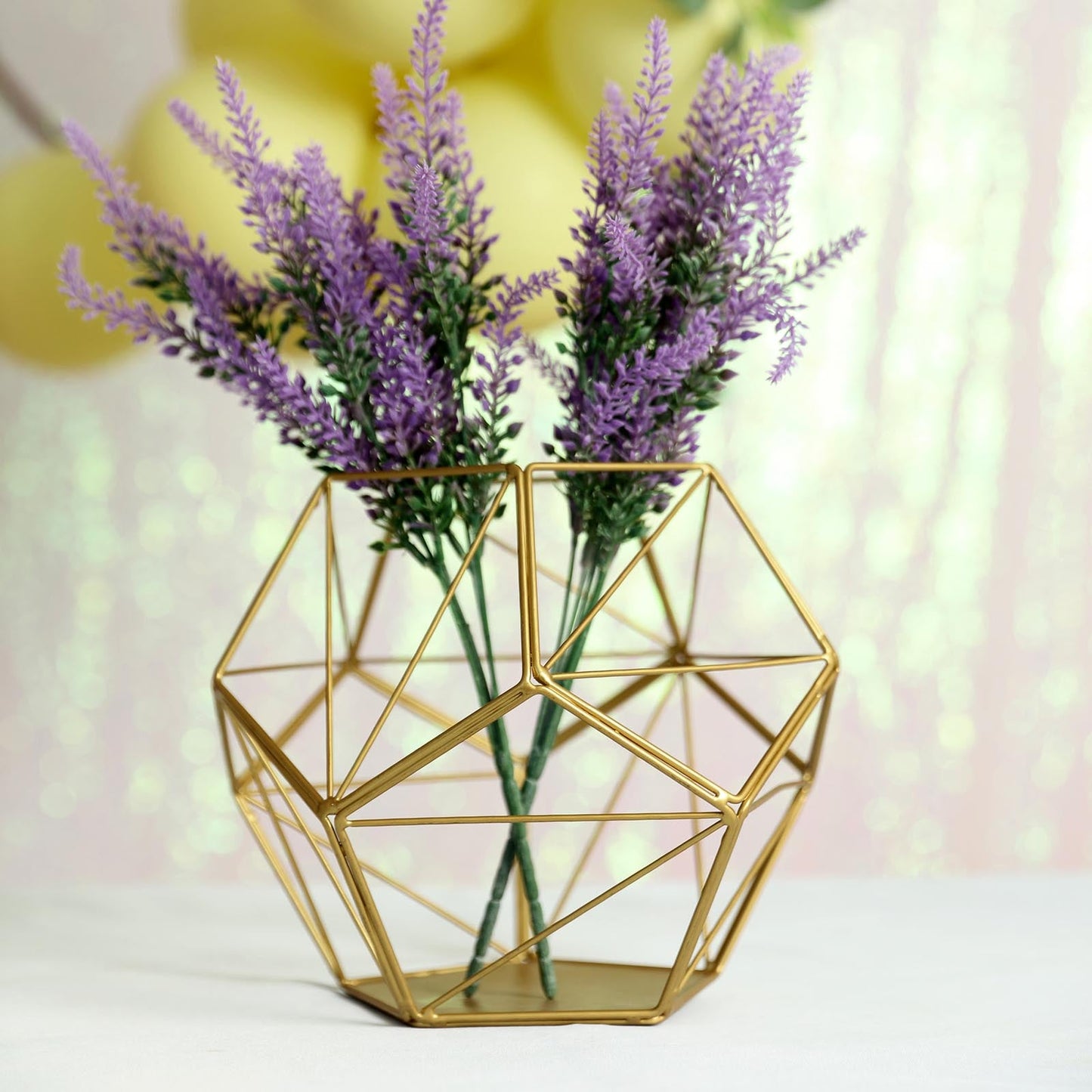 Gold geometric flower stand with lavender flowers.