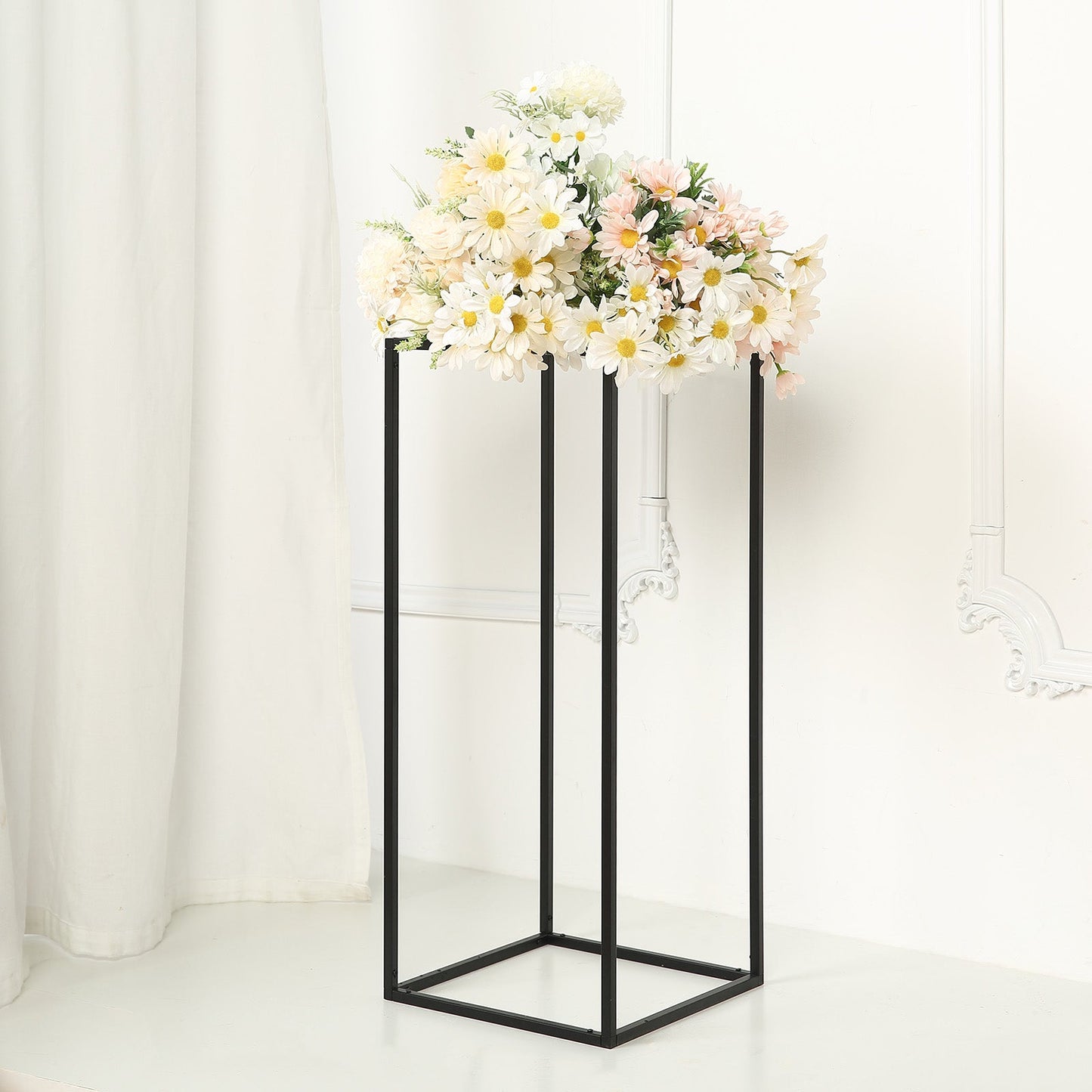 Matte black metal rectangular flower stand with floral arrangement on top.