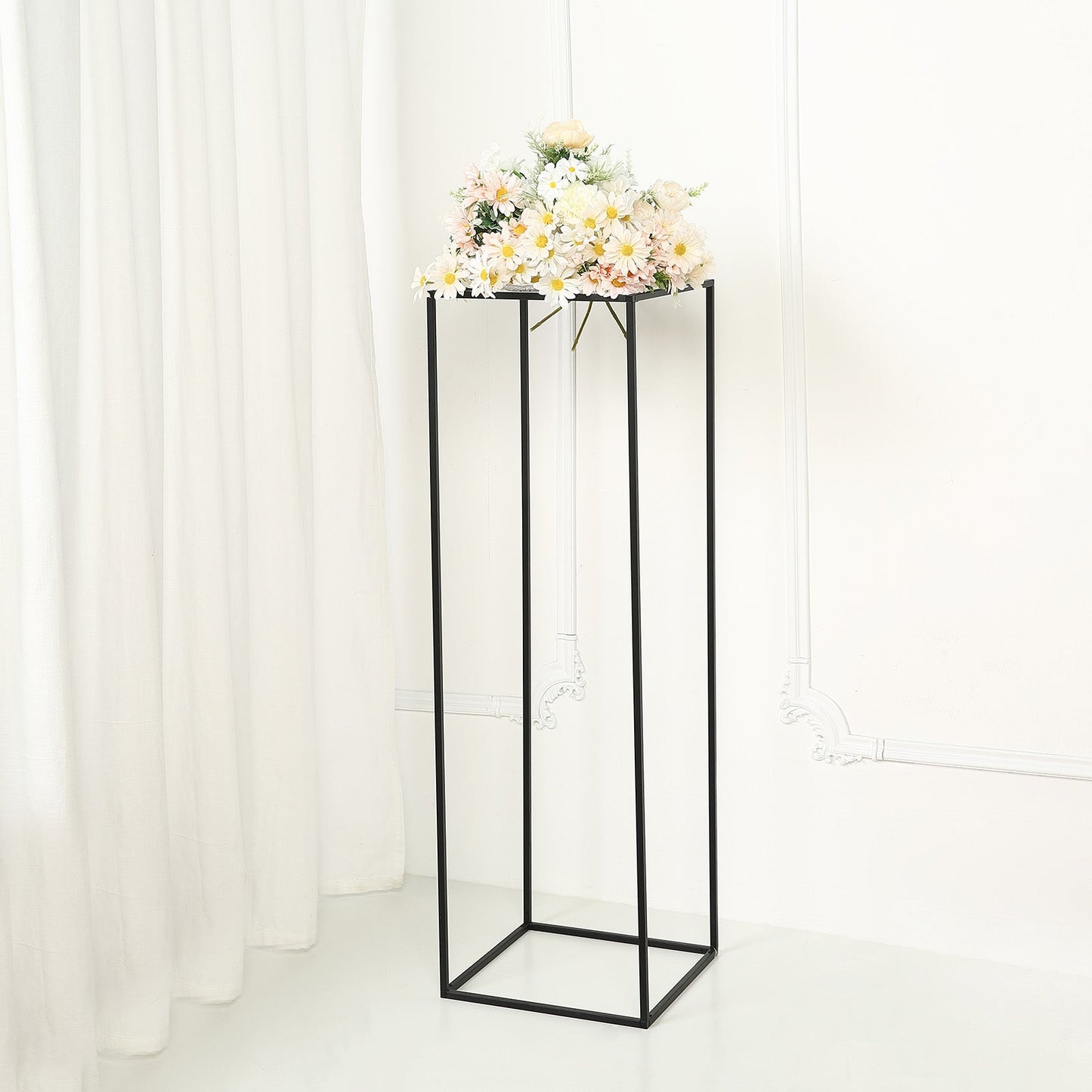 Matte black geometric flower stand with floral arrangement on top.