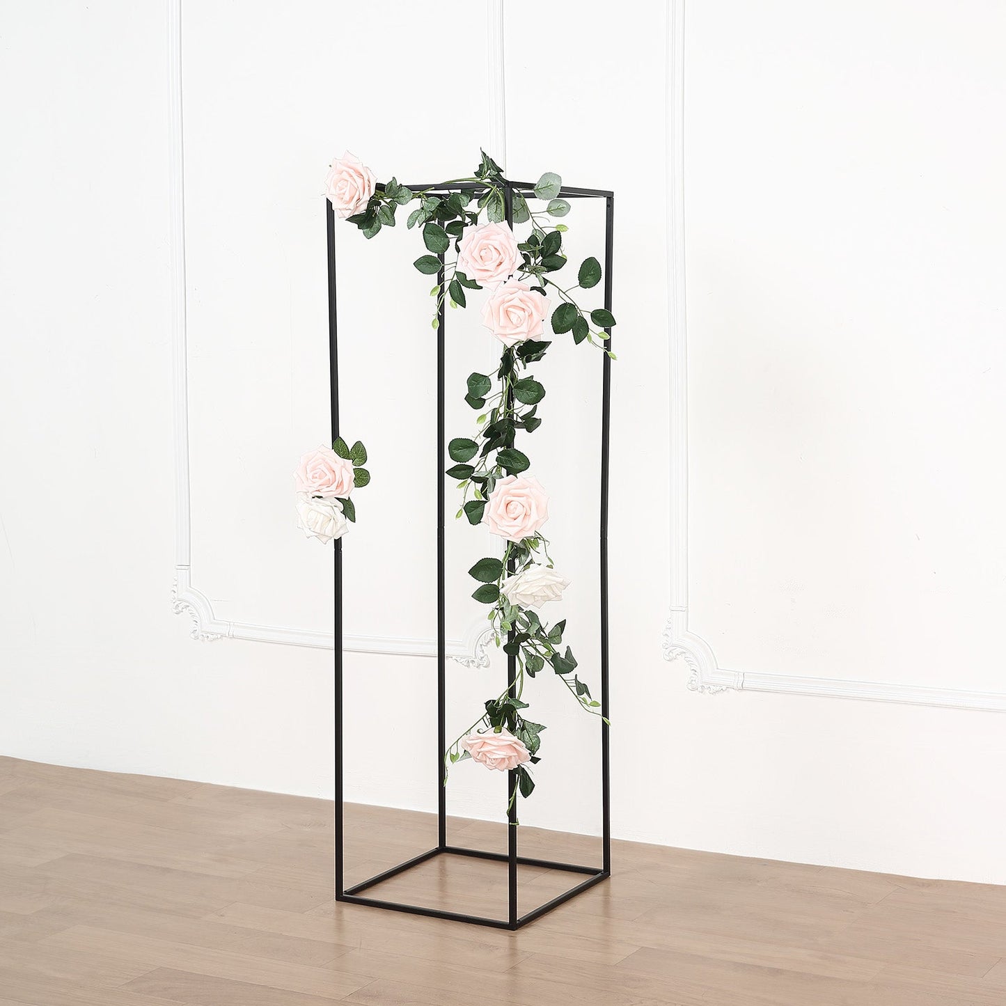 Matte black metal wedding flower stand with pink roses and greenery.