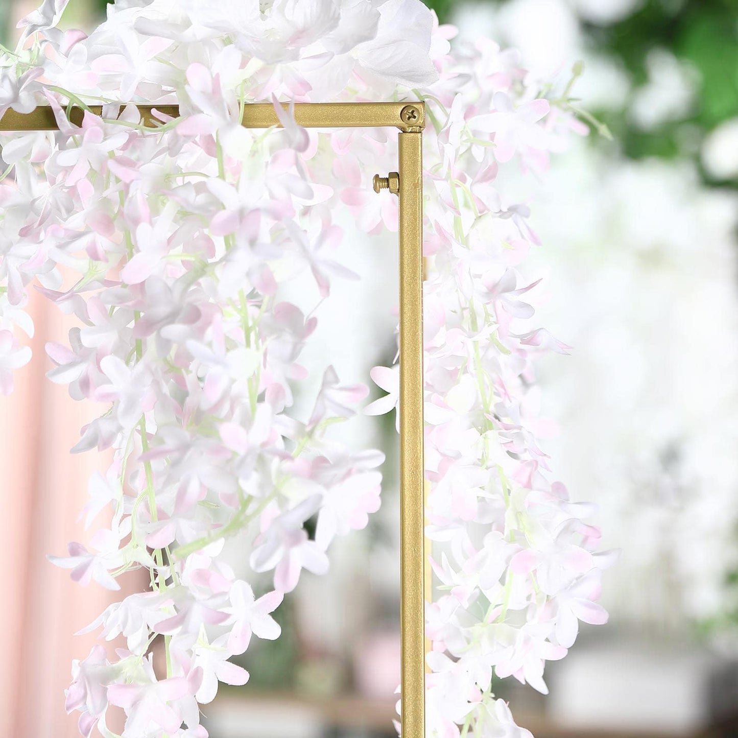 Matte gold metal frame flower stand with pink floral accents.