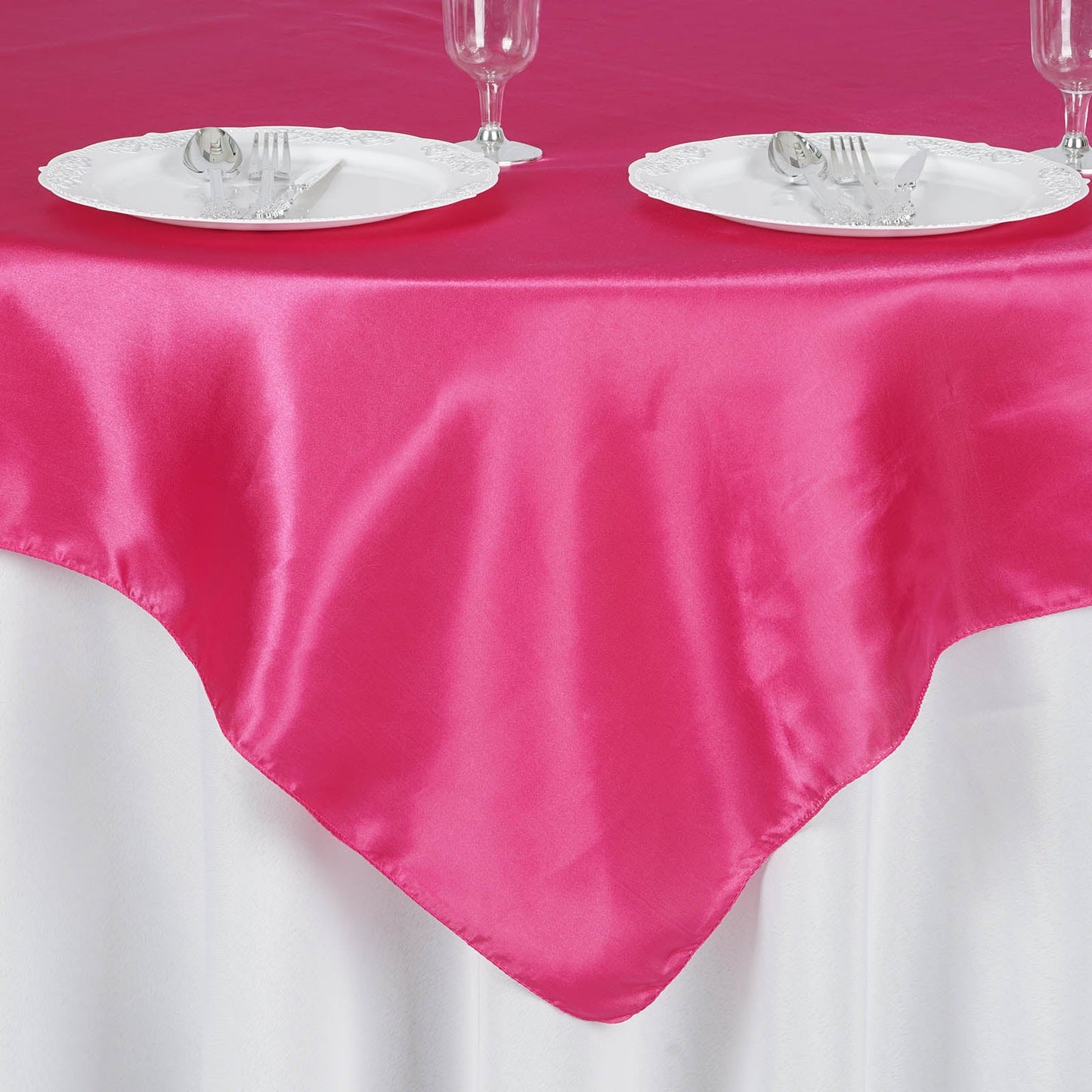 Fuchsia square satin table overlay on a white tablecloth.