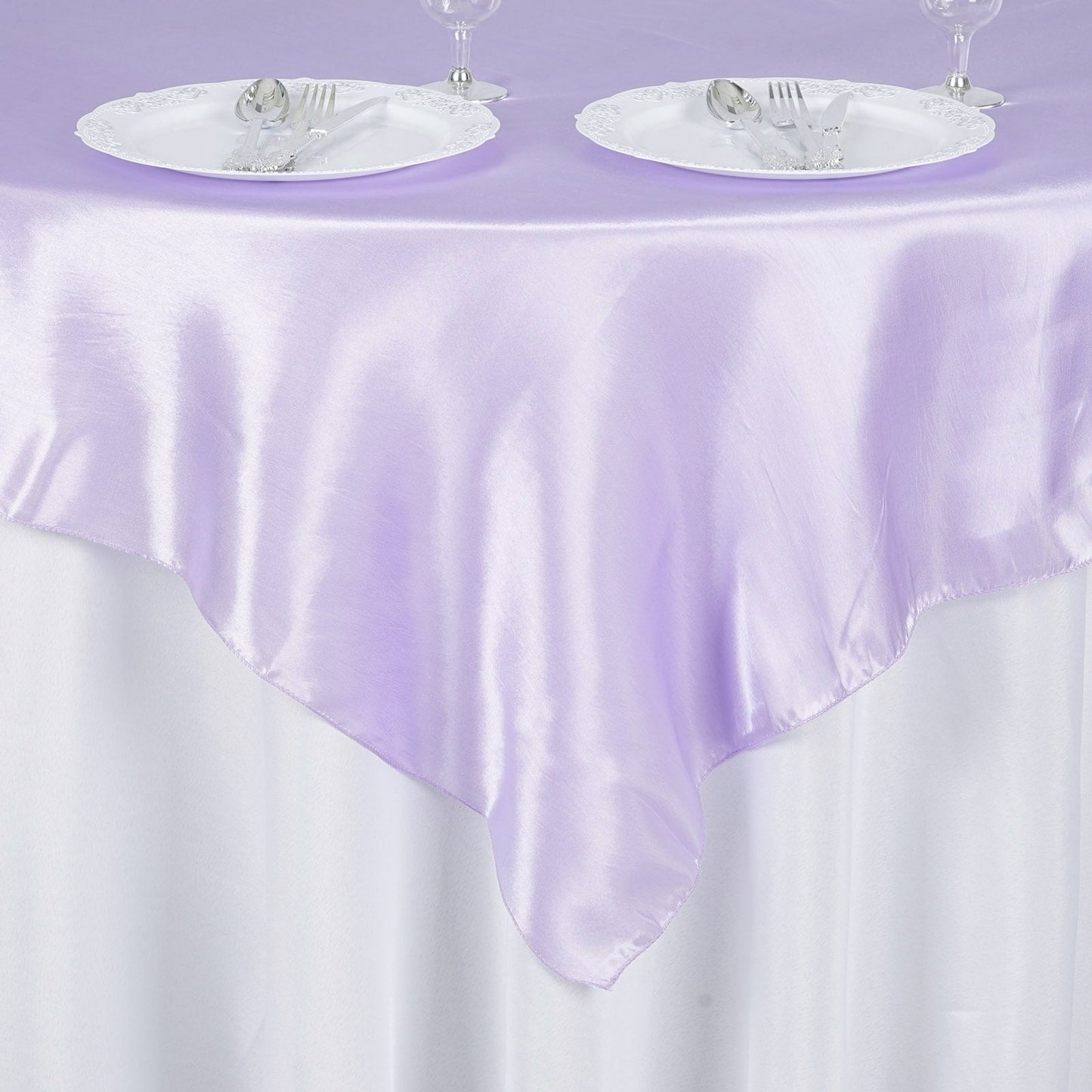 Lavender lilac satin table overlay on a round table with plates and cutlery.