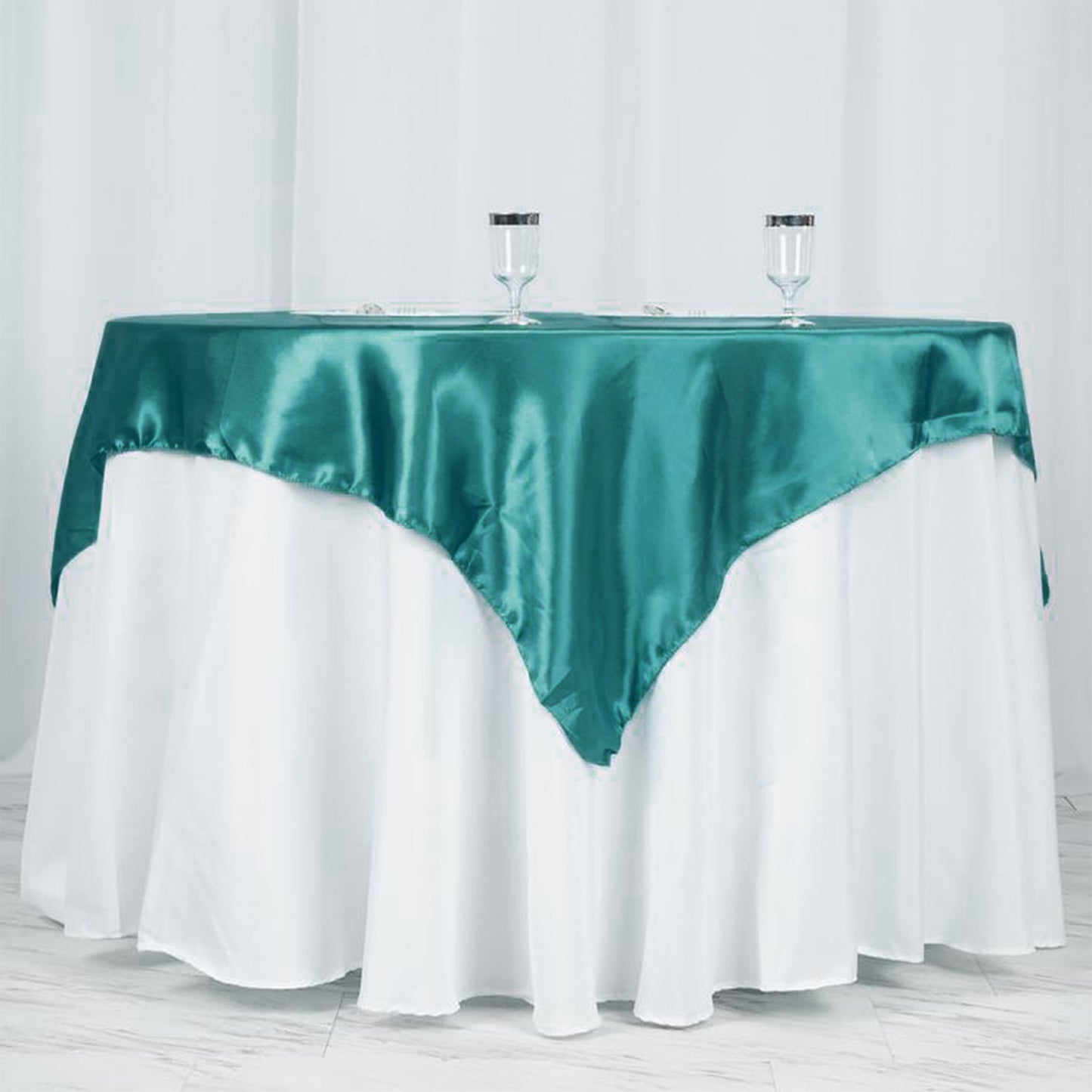 Turquoise satin table overlay draped over a white tablecloth.