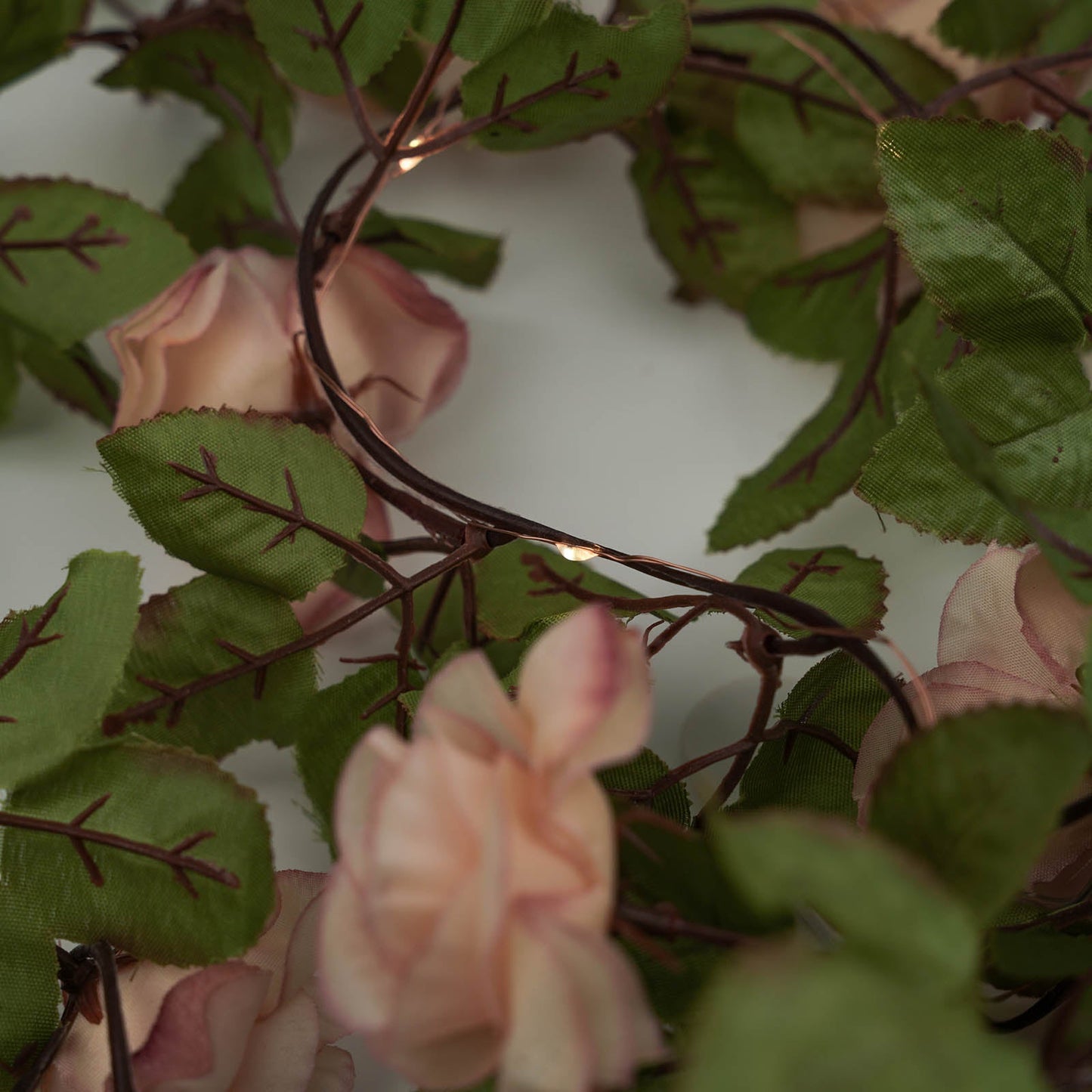 Blush silk rose flower garland vine string lights with warm white LEDs.