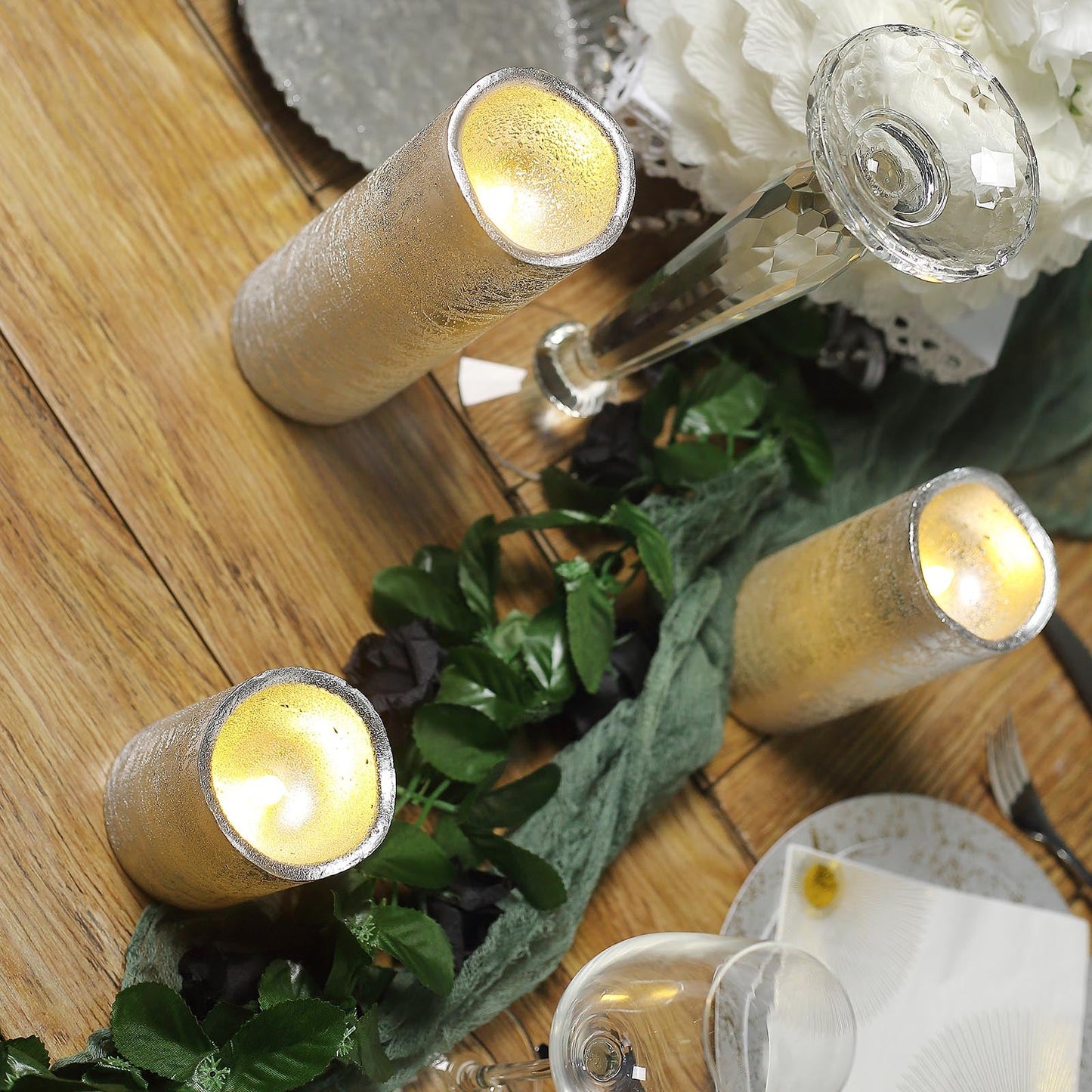 Metallic silver LED pillar candles on a rustic table setting.