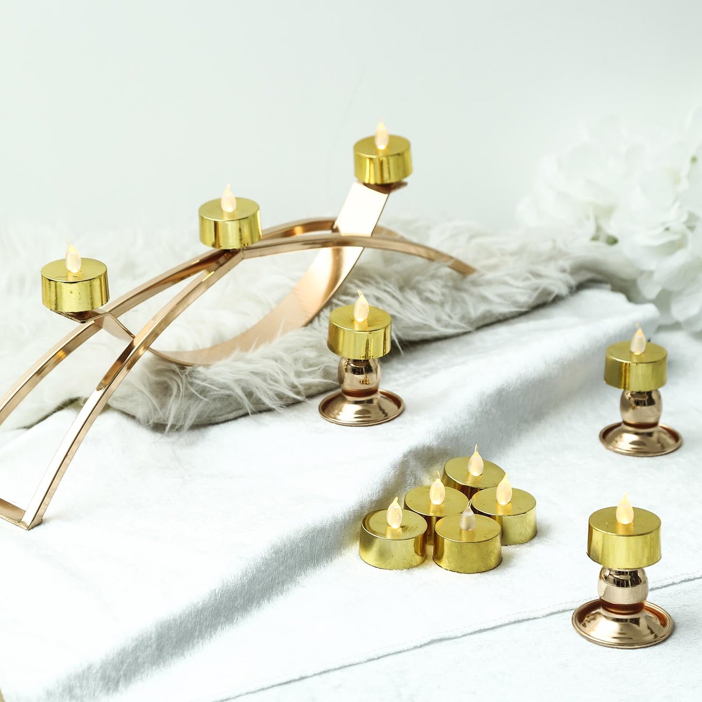 Metallic gold LED tealight candles on a decorative surface.
