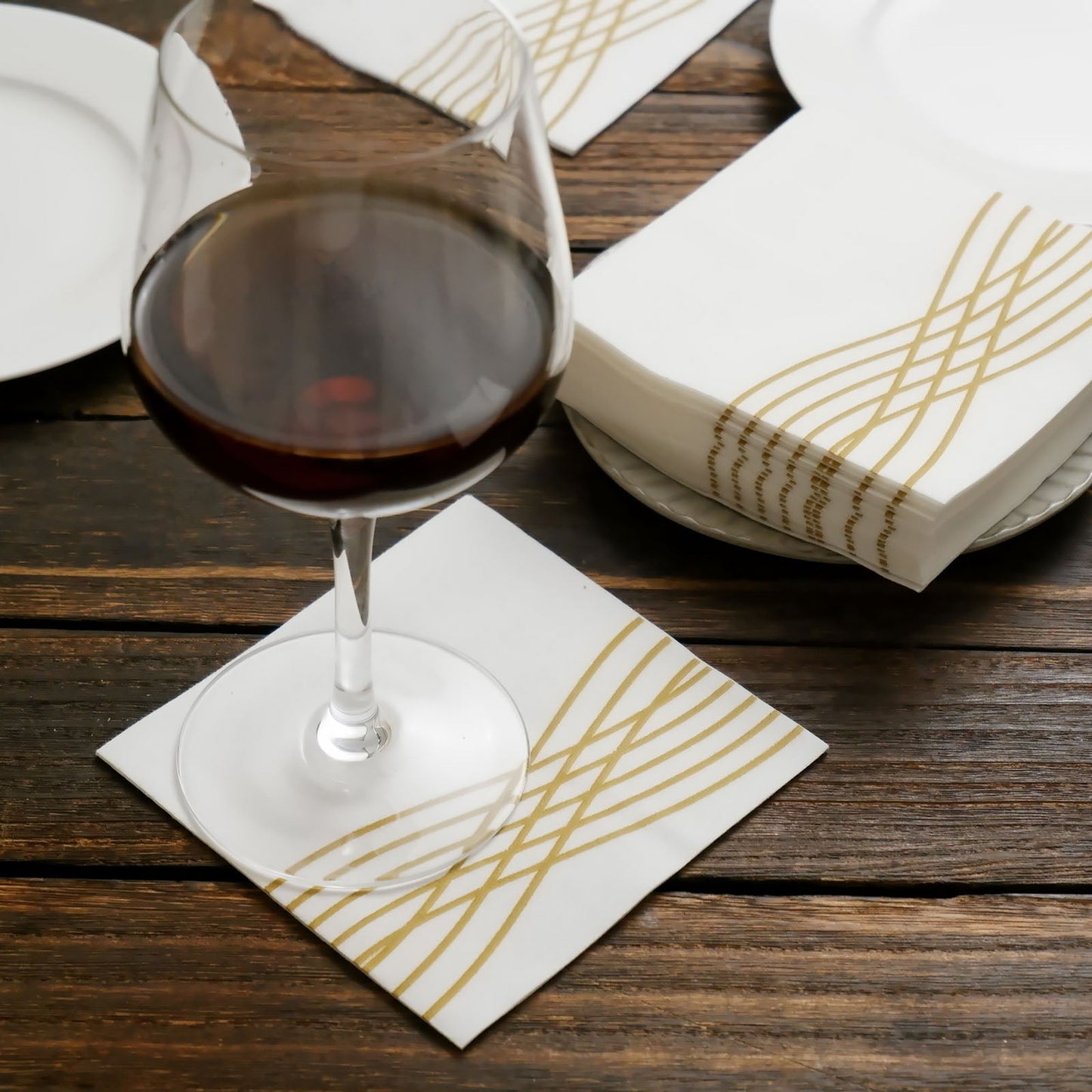 White linen-feel cocktail napkin with gold waves print.