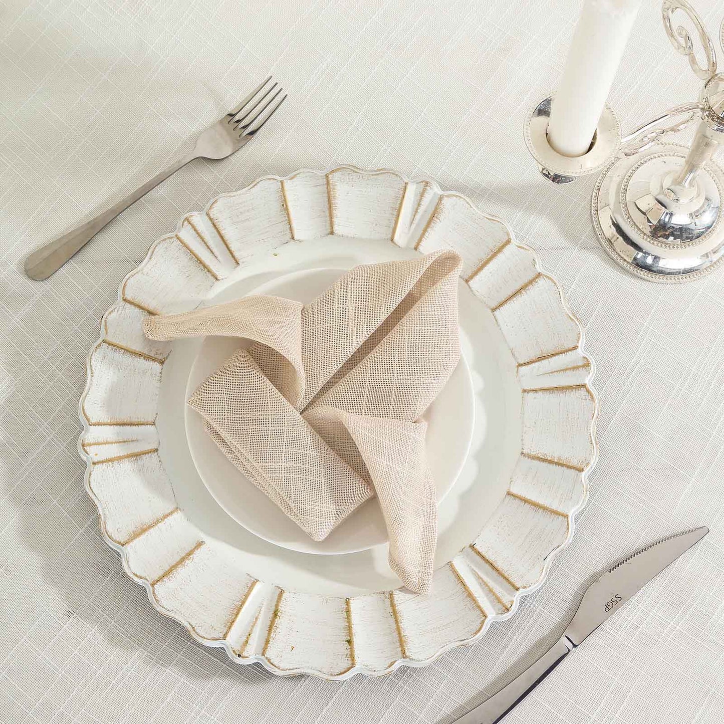 Beige slubby textured cloth dinner napkin on a decorative plate.