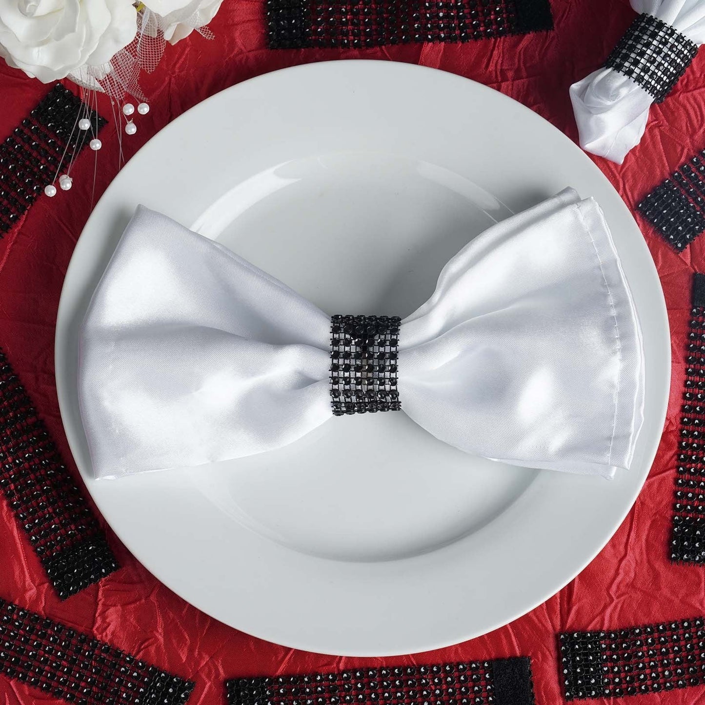 Black diamond rhinestone napkin ring on a white napkin and red table setting.