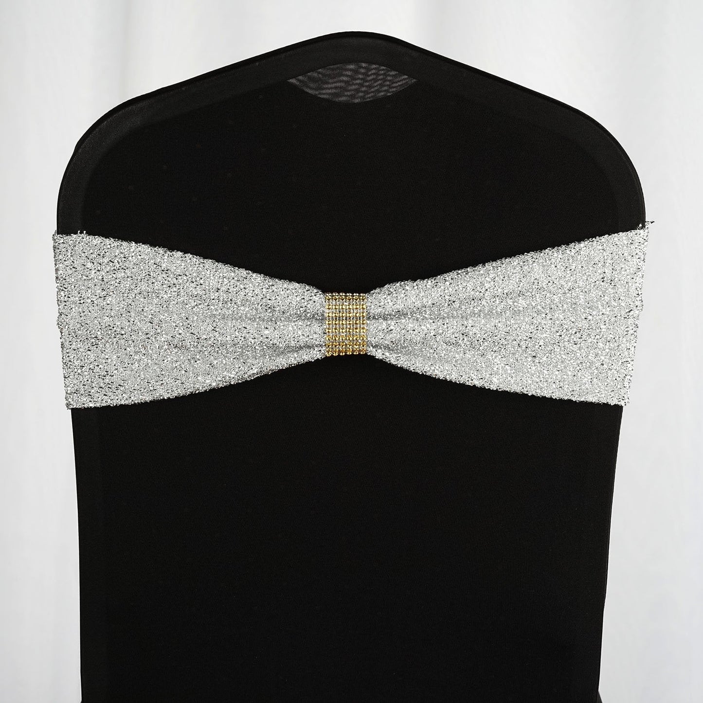Gold rhinestone chair sash with a sparkling design on a black chair.