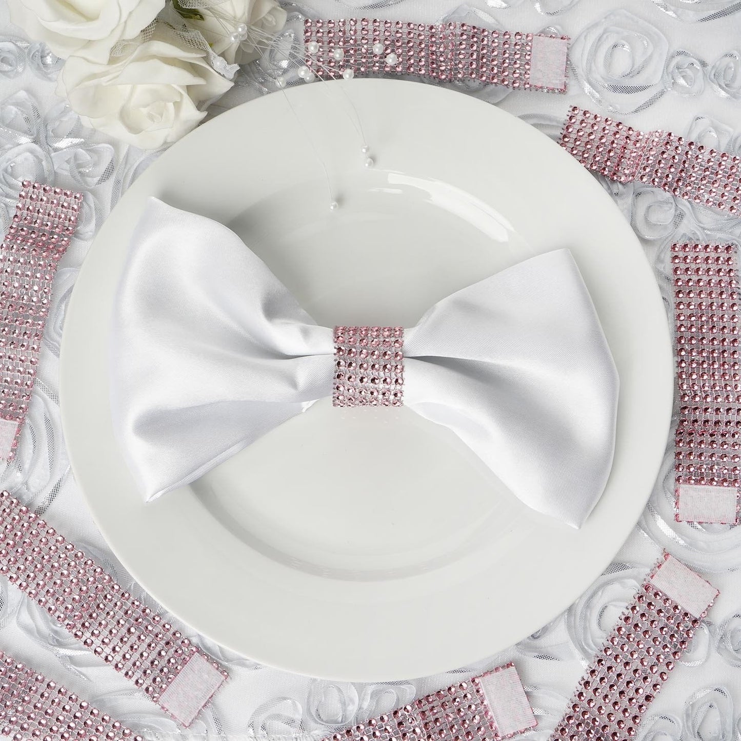 Pink diamond rhinestone napkin rings and chair sashes on a white plate.